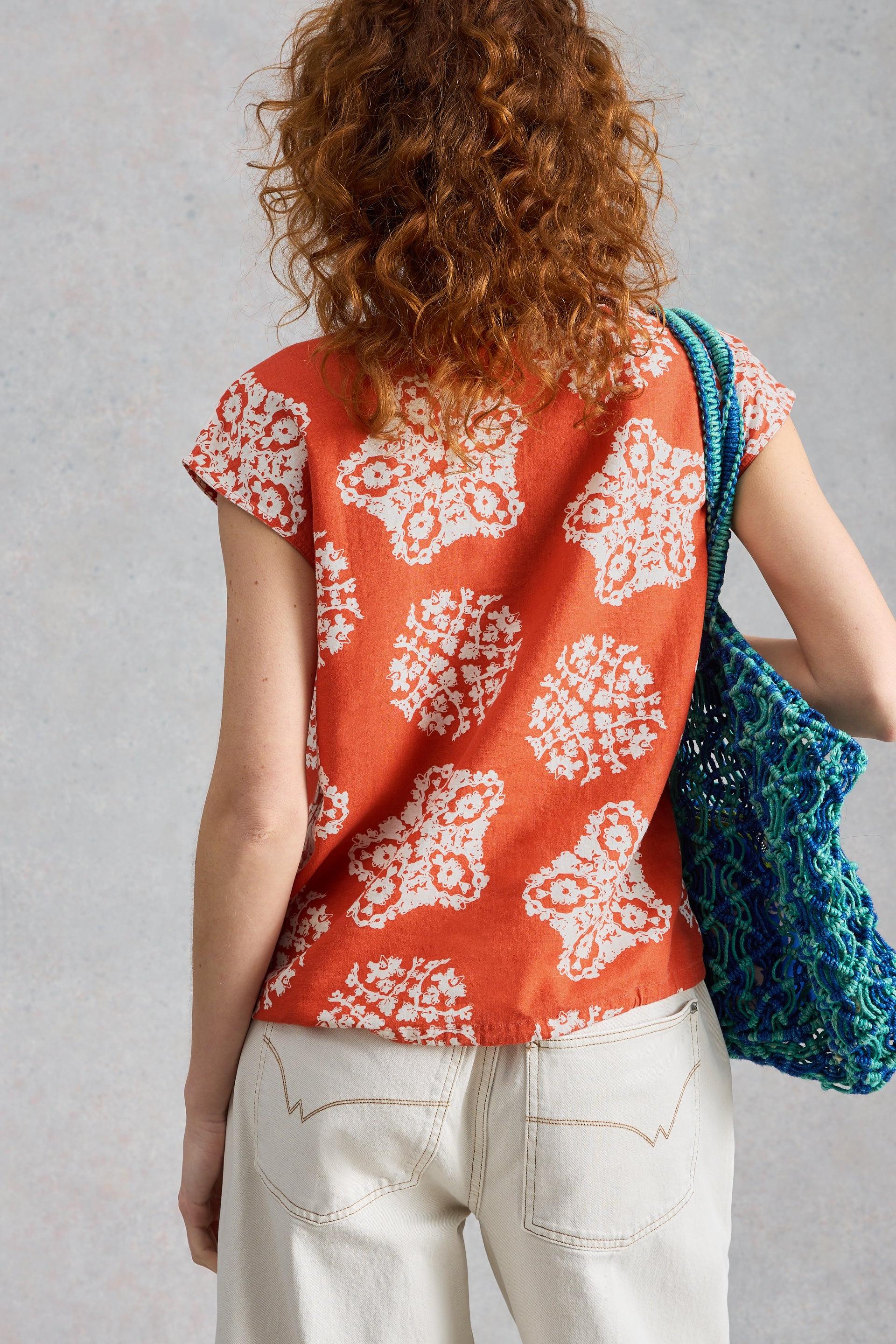 Person wearing a red floral linen blouse with a gray background
