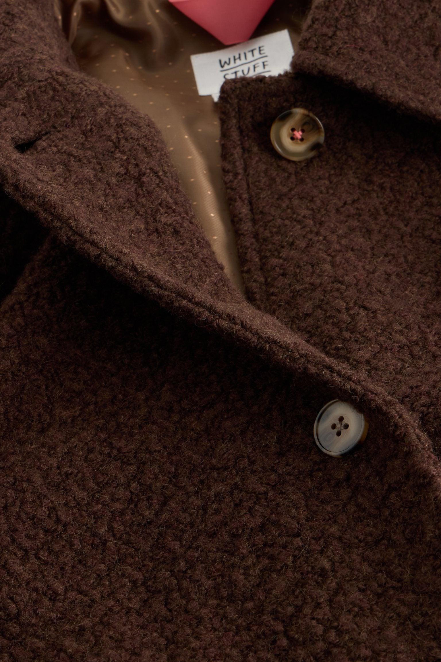 Close-up of a brown wool White Stuff winter coat featuring textured fabric and button details.