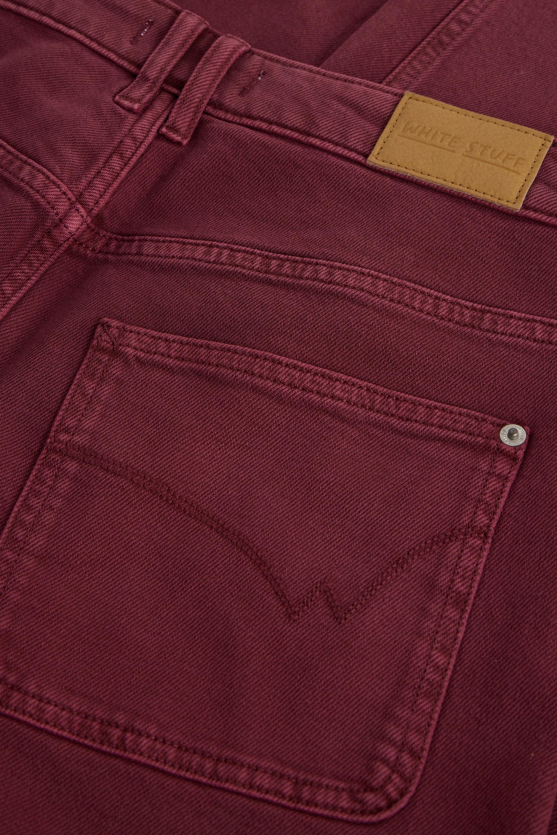 Close-up of burgundy White Stuff organic cotton jeans showing the back pocket and leather brand label.