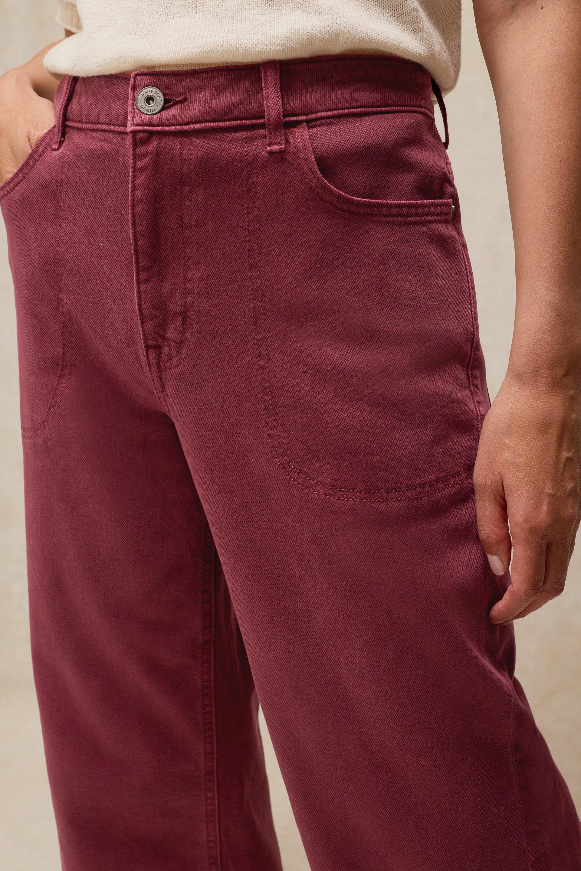 Person wearing burgundy White Stuff trousers made from organic cotton, captured in a studio shot.