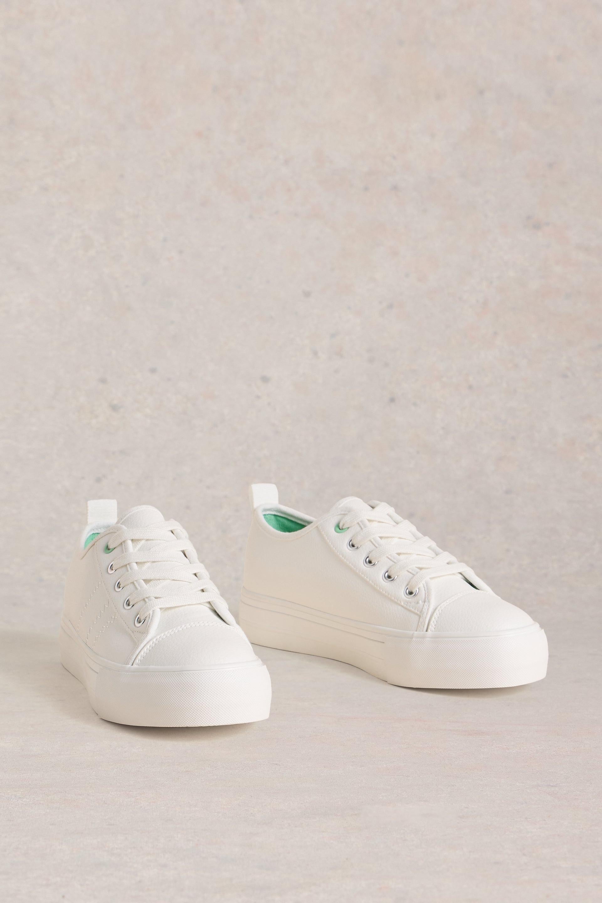 A pair of white canvas platform sneakers by White Stuff against a neutral background.