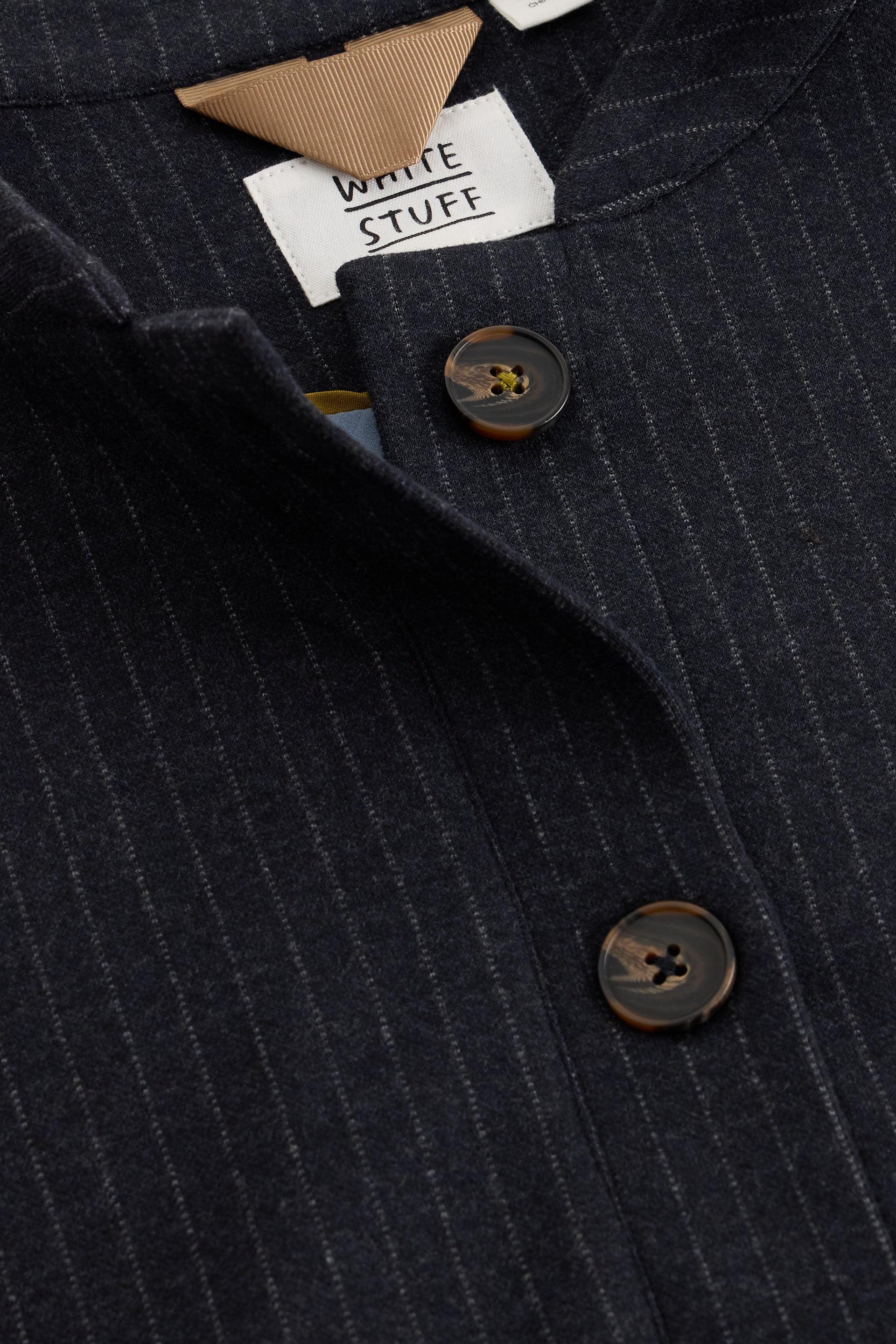 Close-up of a navy pinstripe jacket featuring White Stuff branding on the neck label and brown buttons