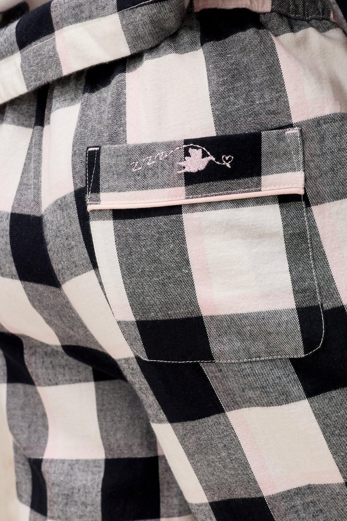 Close-up of White Stuff organic cotton pyjama bottoms with a black and pink check print and a back pocket detail.