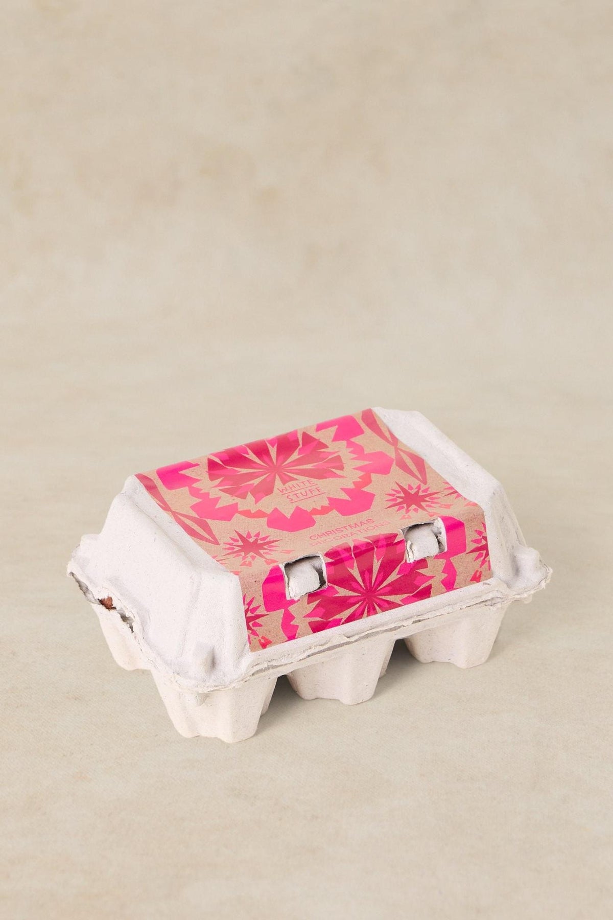 A closed White Stuff cardboard egg-style carton used for storing felt wool Christmas decorations.
