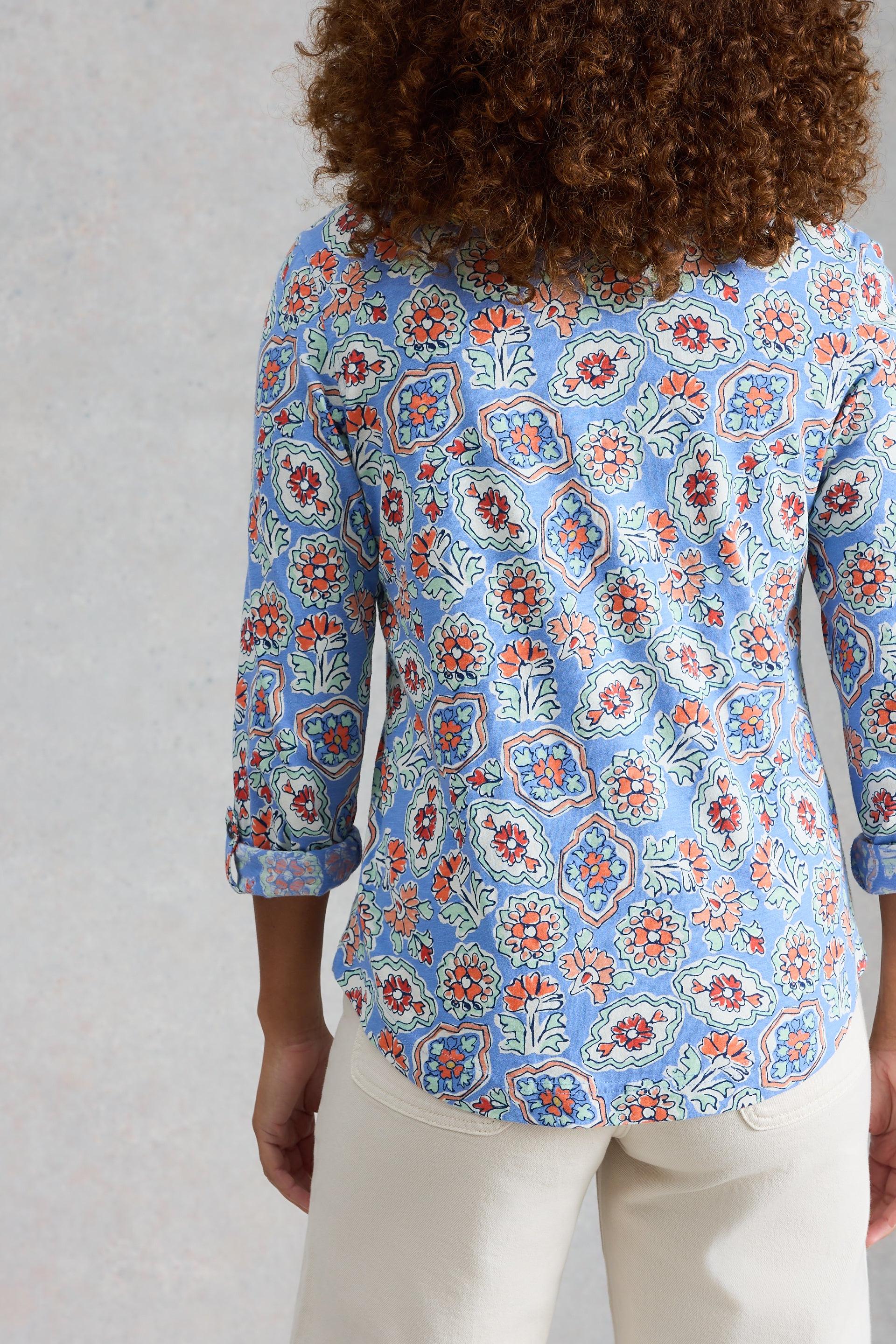 Person wearing a blue floral cotton shirt against a plain background