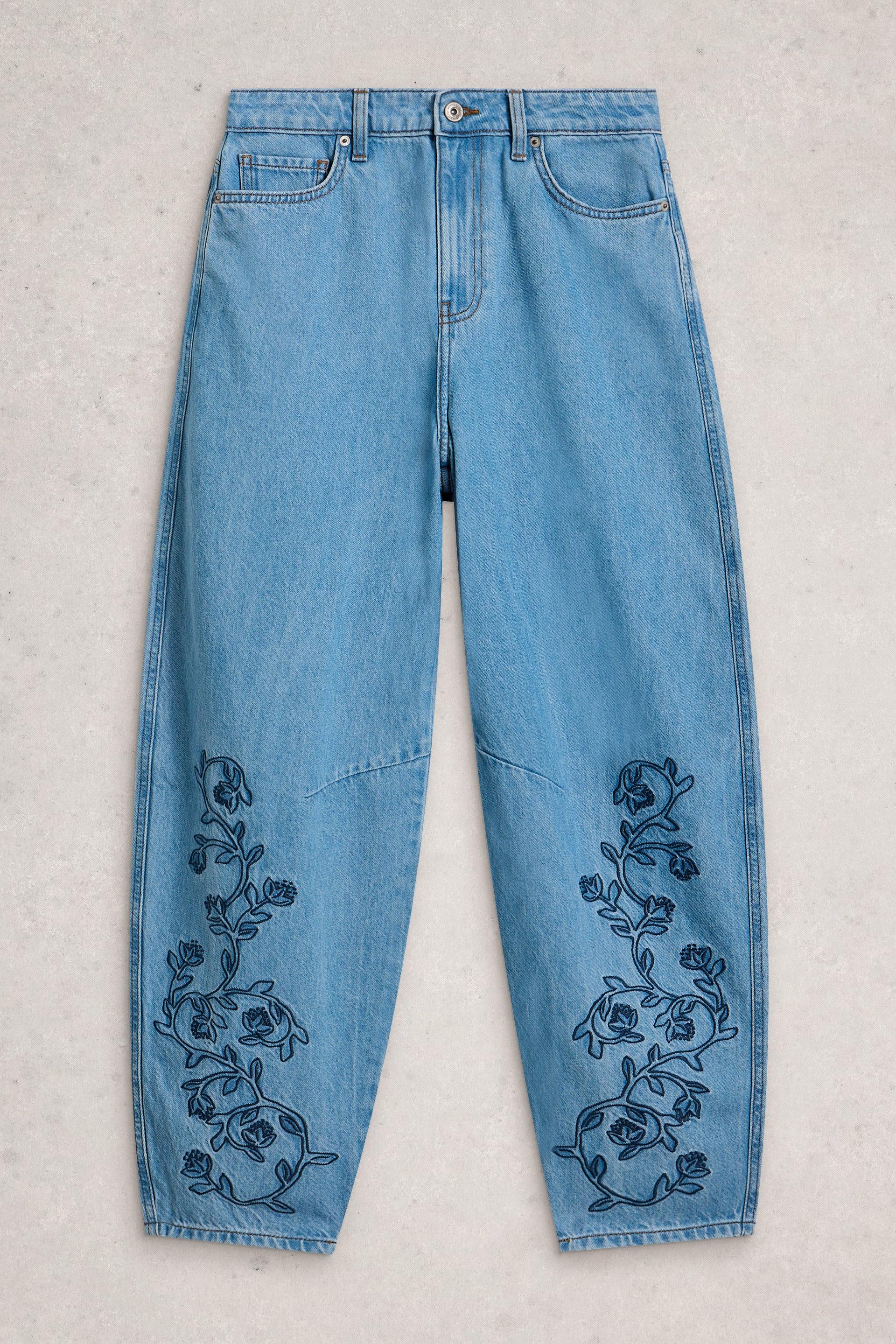 Light blue barrel leg jeans with floral embroidery on a light gray background