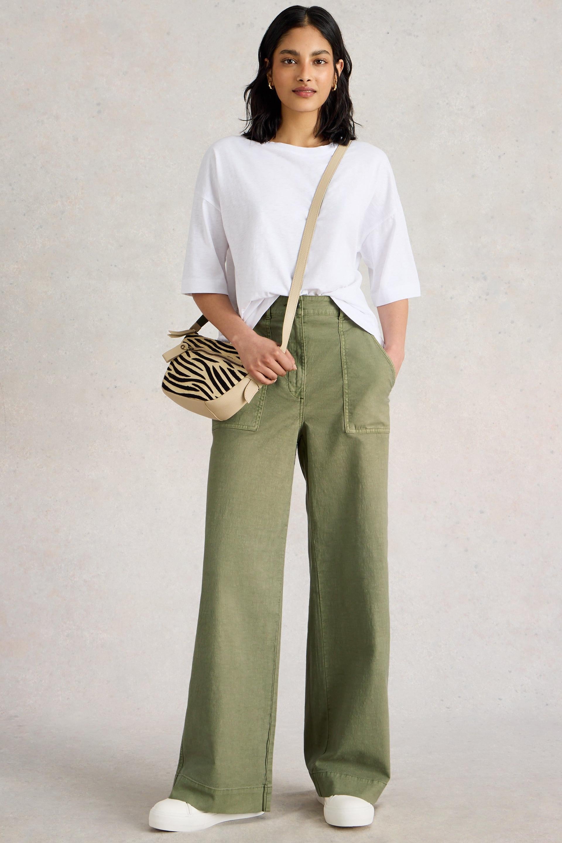 Womand wearing a white stuff cotton boxy tee with green wide leg trousers and crossbody bag
