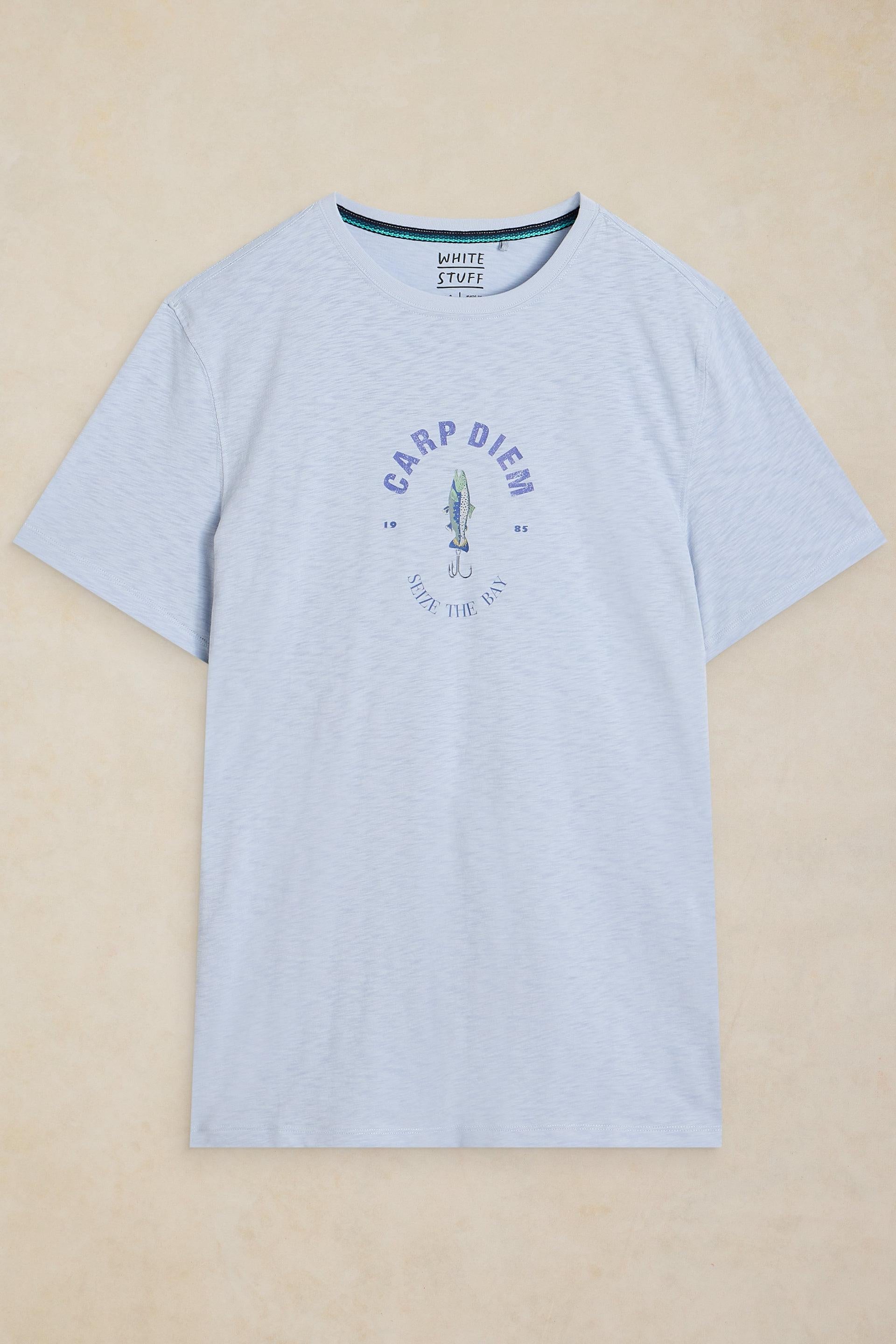 A light blue heather crewneck t-shirt with a circular graphic on the chest reading 'CARP DIEM' and 'Seize The Bay', displayed flat against a warm beige background.