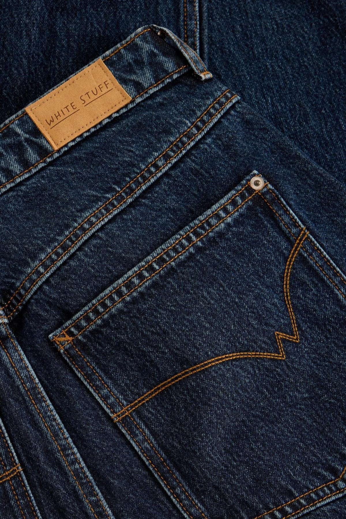 Close up of a White Stuff dark denim jeans pocket with contrast stitching and leather brand label