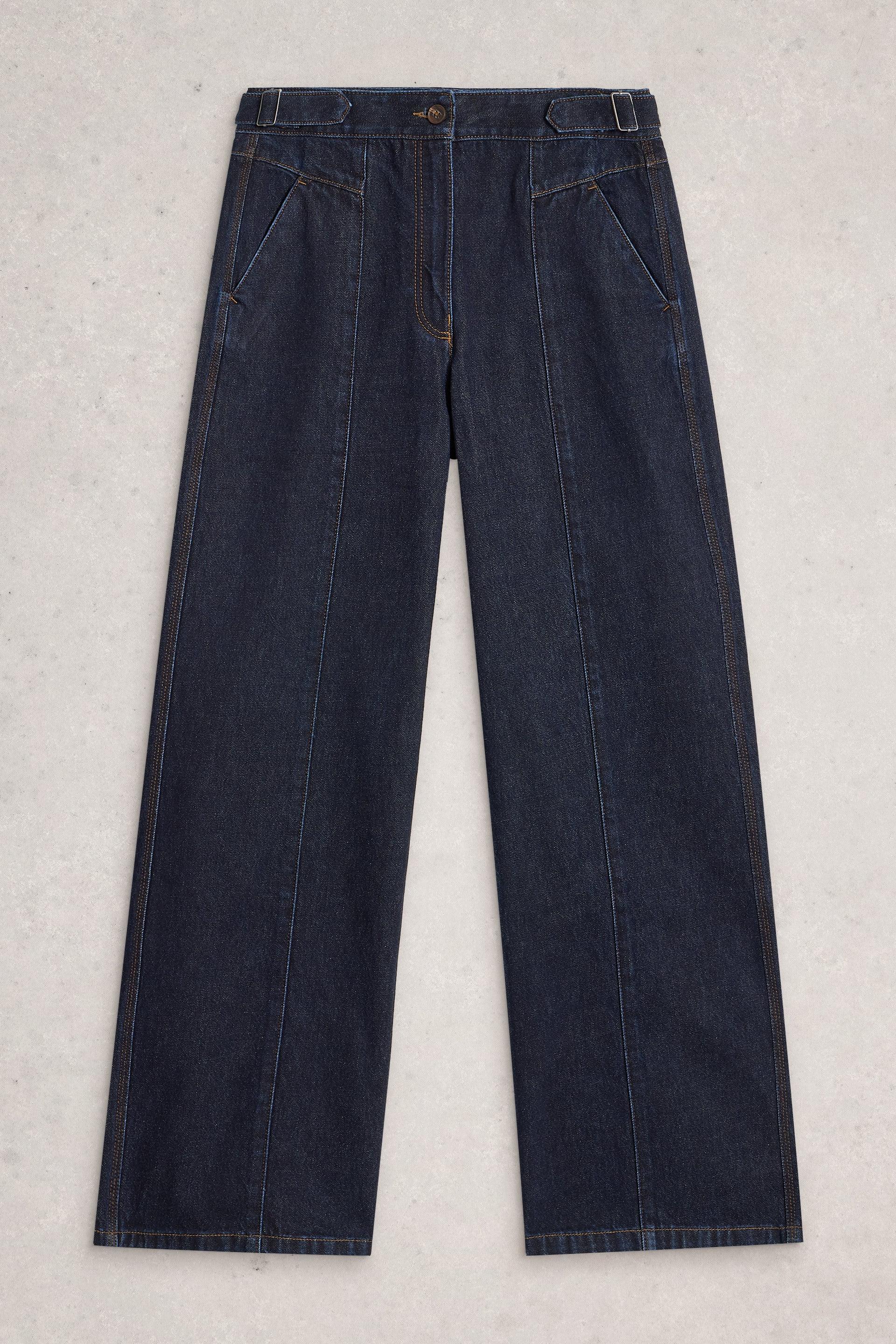 Dark wash organic cotton denim trousers with side buckle details displayed flat on a light grey background.