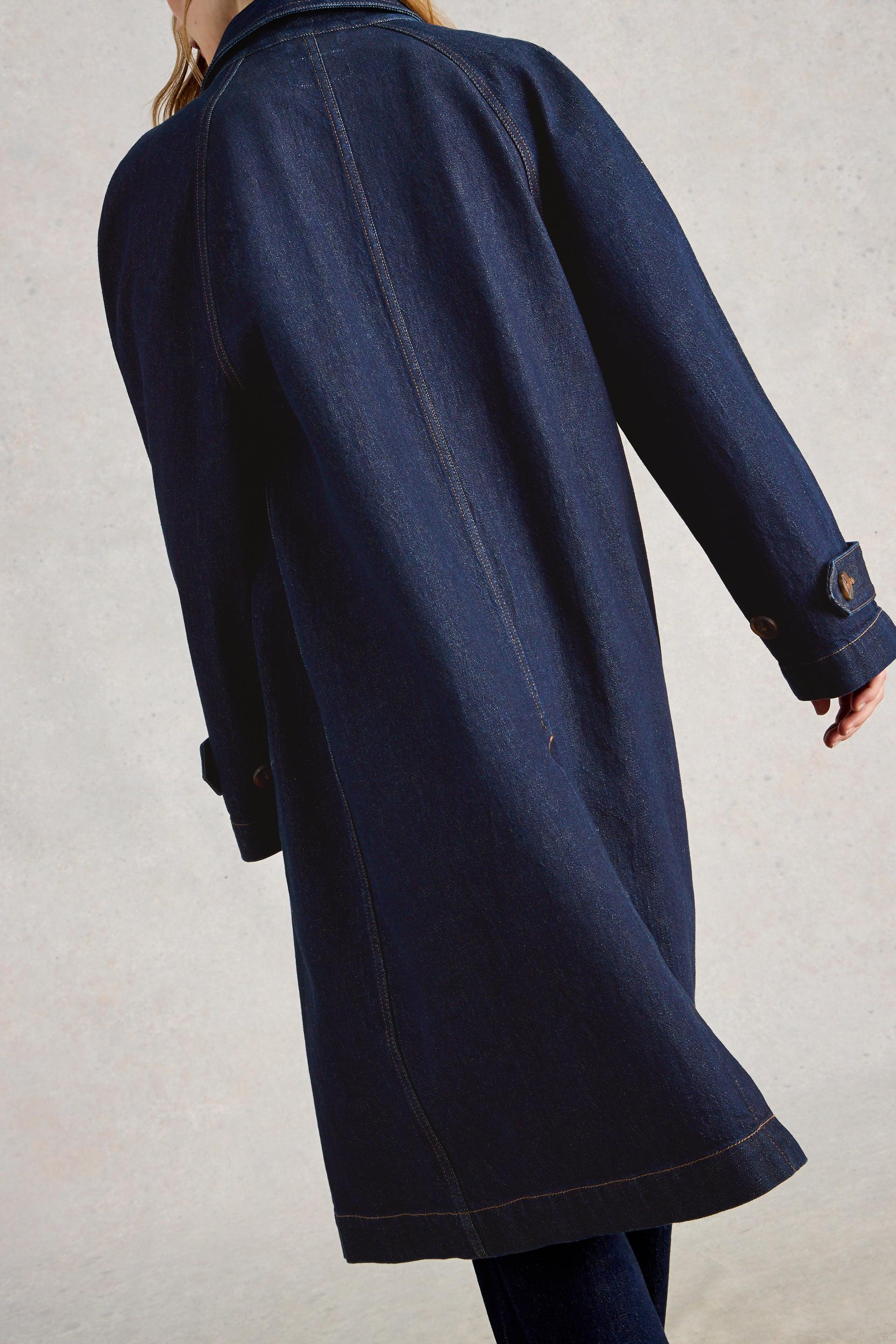 Woman wearing a dark indigo denim trench coat made from organic cotton