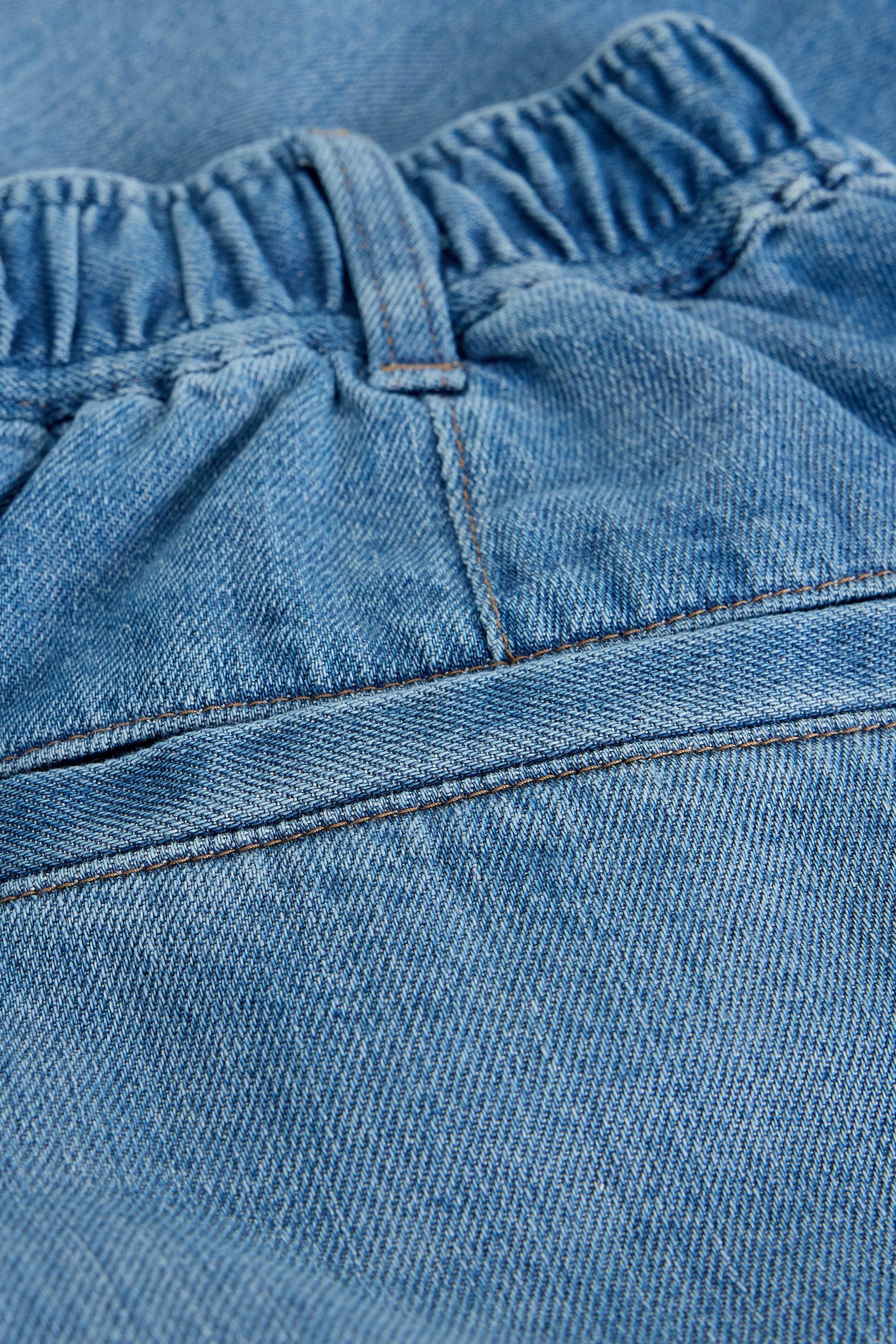 Close-up of blue denim shorts with stitching and pocket details 