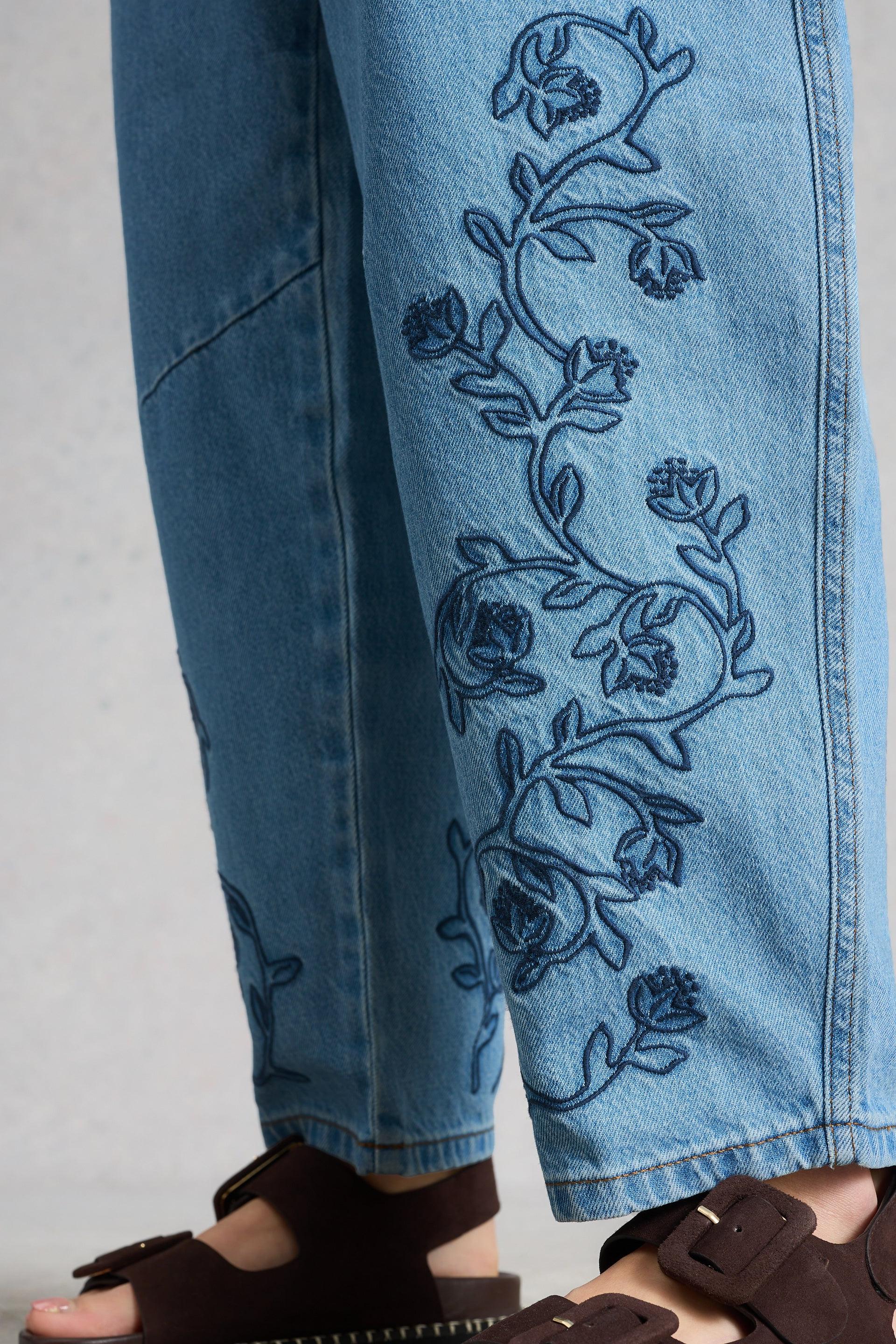 Blue jeans with floral embroidery on a plain background