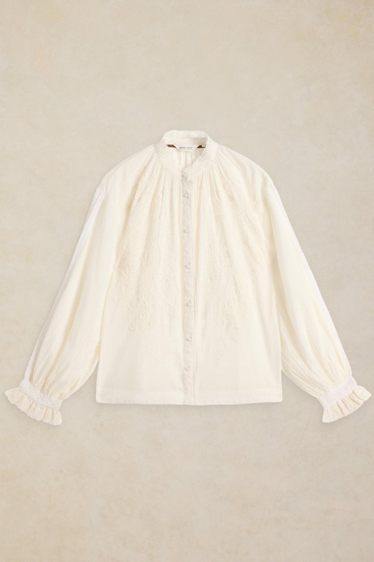 White Stuff women's organic cotton blouse with delicate embroidery and ruffled cuffs displayed against a neutral background.