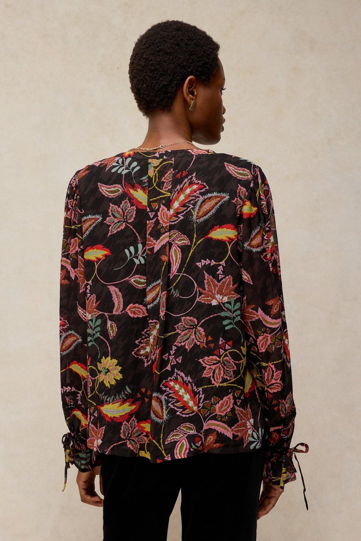 A model from the back wearing a long-sleeved floral White Stuff viscose shirt with tie cuffs.