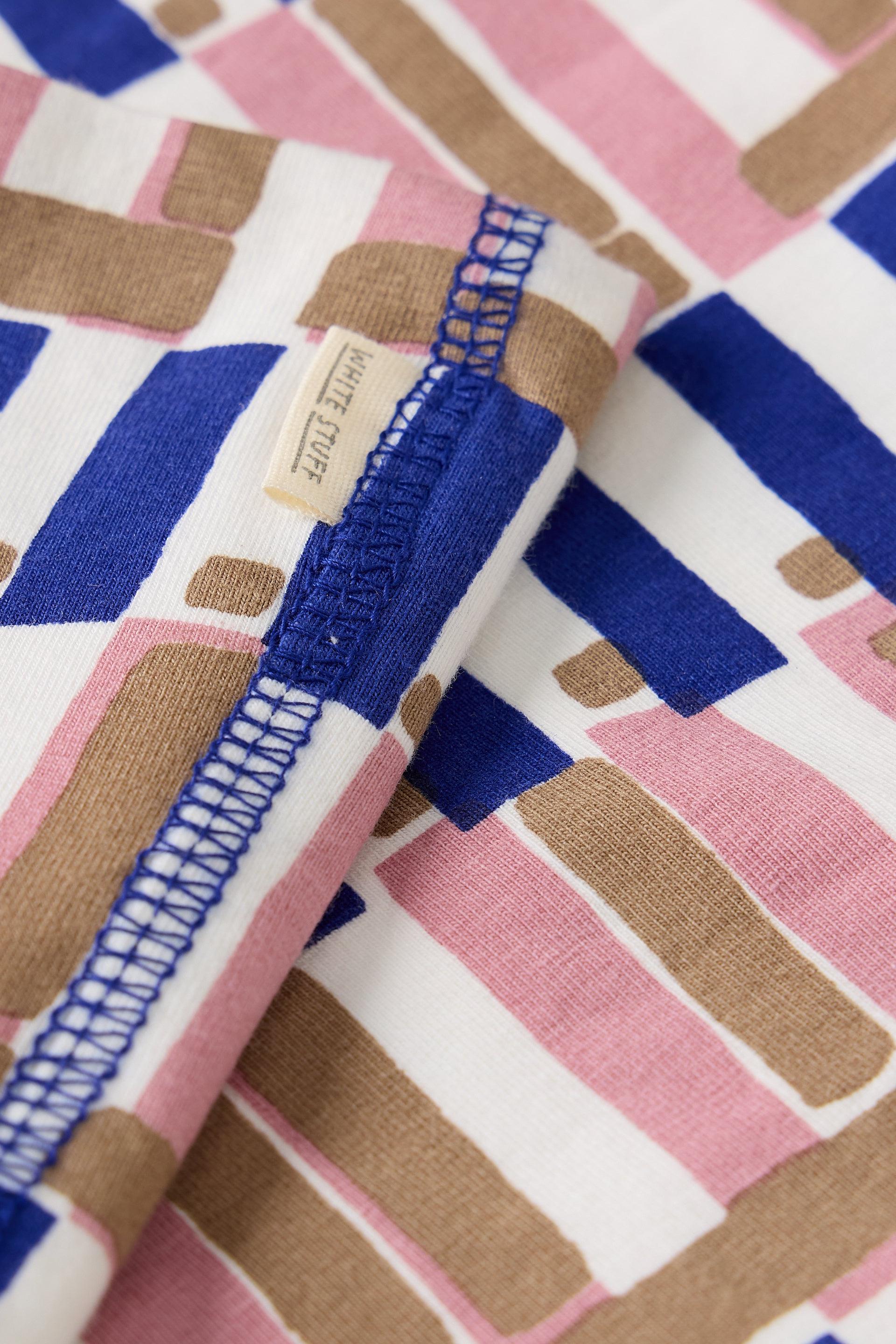 Close-up of white, blue, and tan geometric patterned fabric with a White Stuff clothing brand tag.