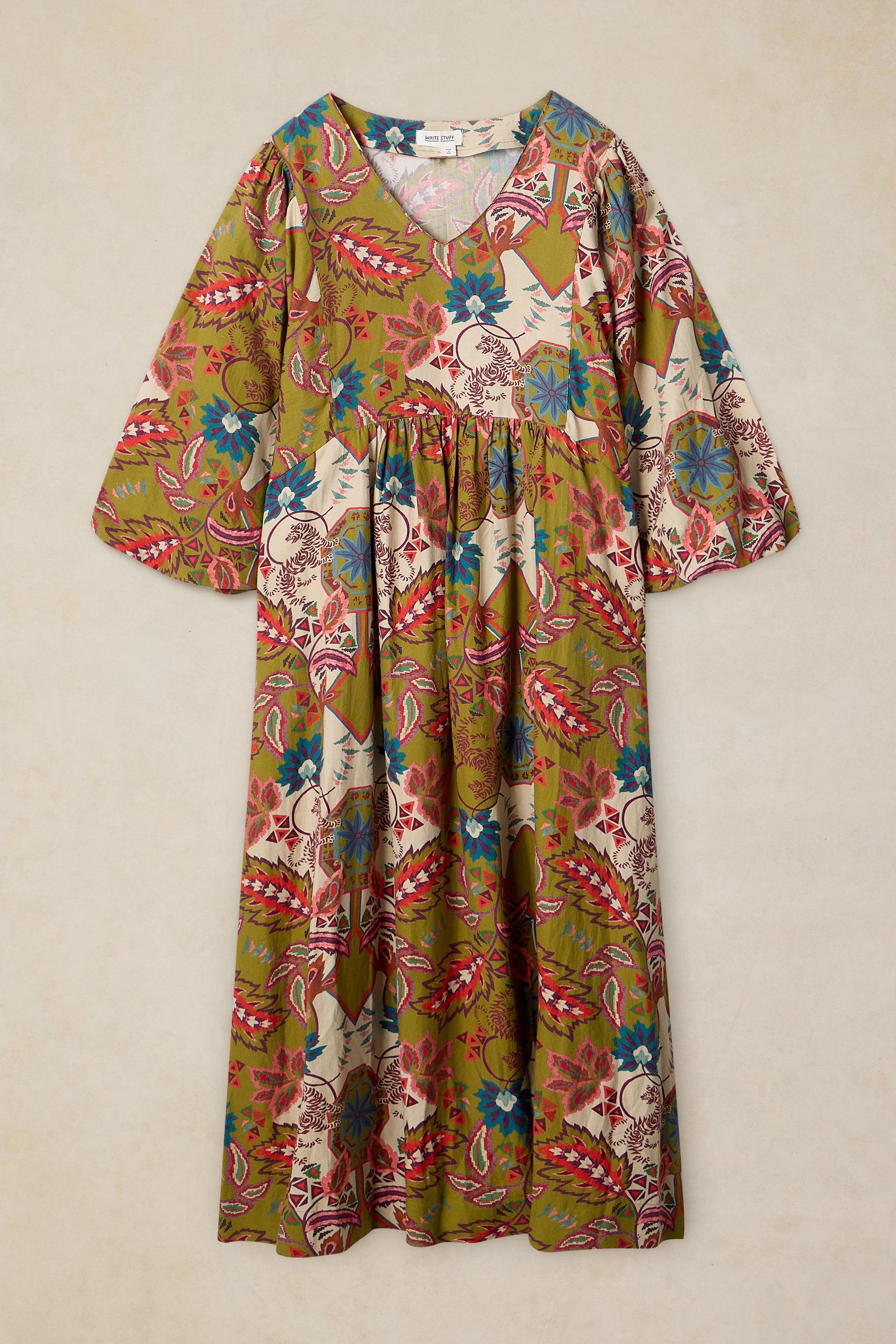 A long-sleeve V-neck maxi dress with a colorful floral and paisley print, laid flat against a neutral beige background.