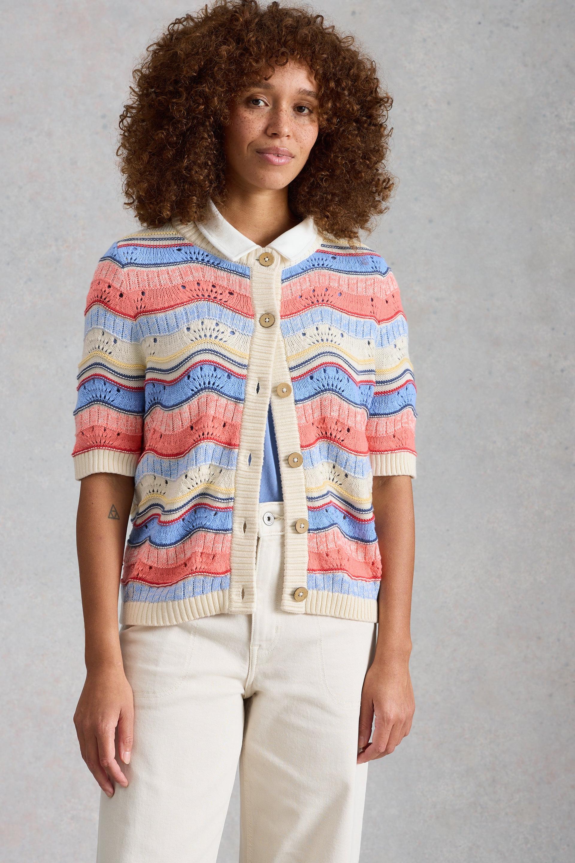 Woman wearing a colorful striped cardigan against a gray background