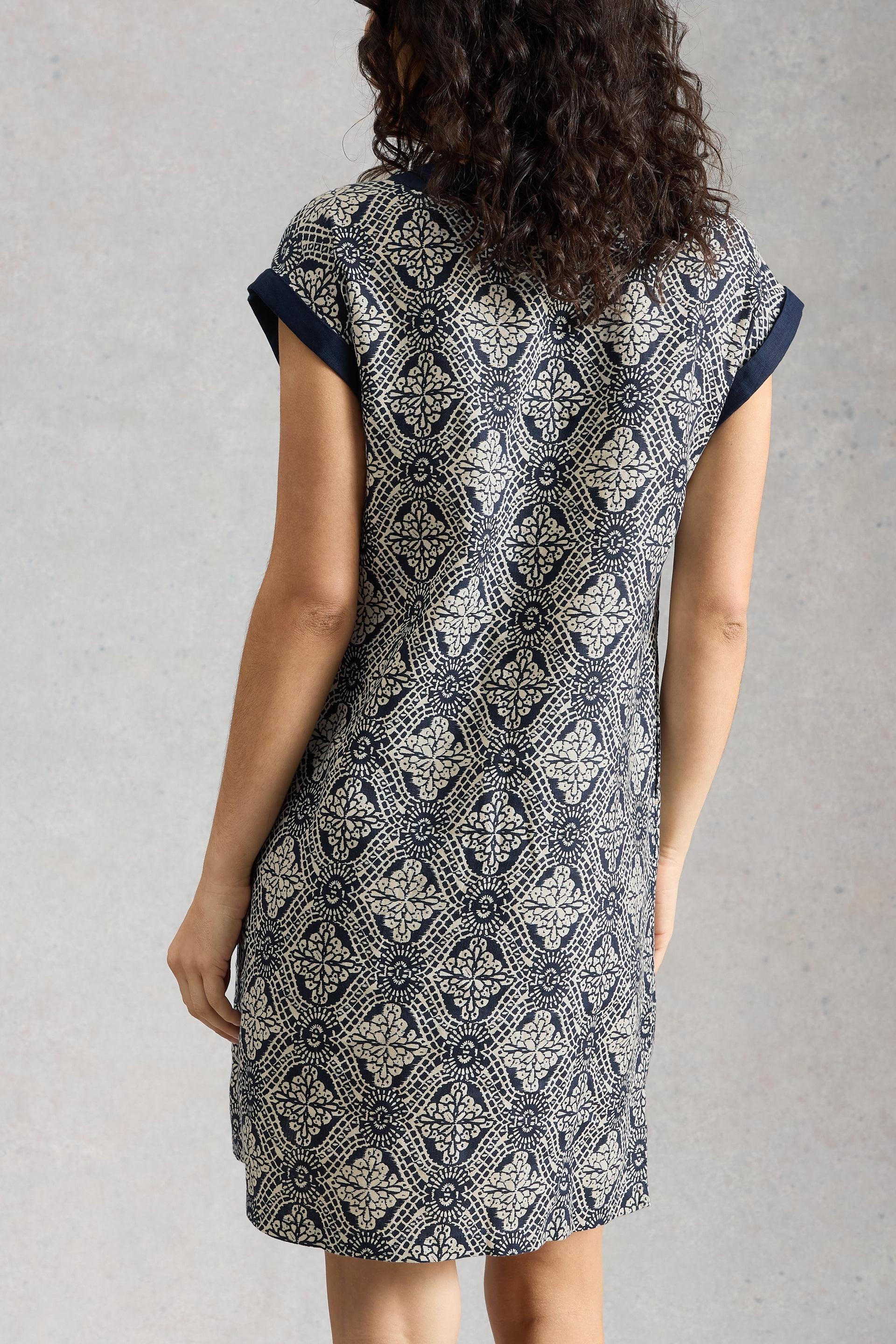 Woman wearing a patterned White Stuff dress against a plain background