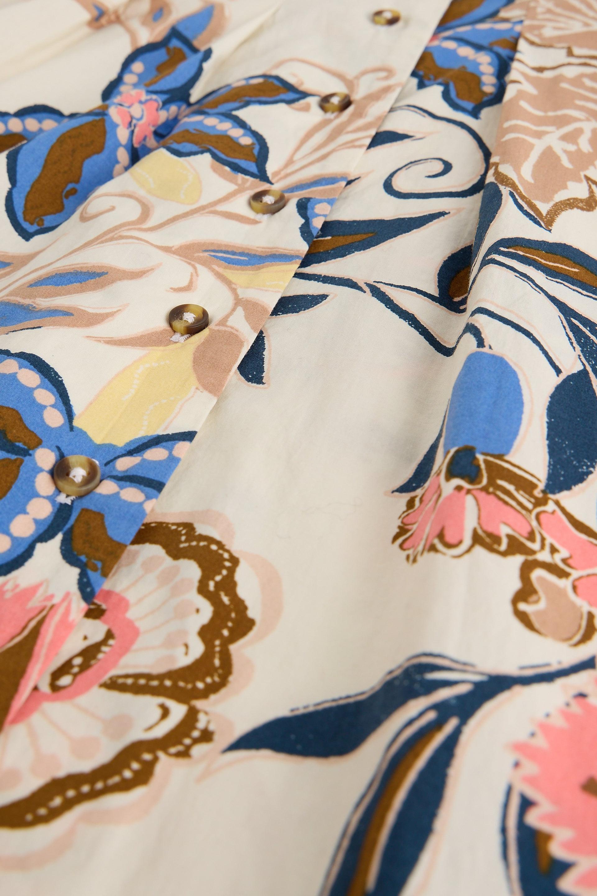 Close-up of floral fabric with blue, pink, and yellow flowers and buttons on a beige background