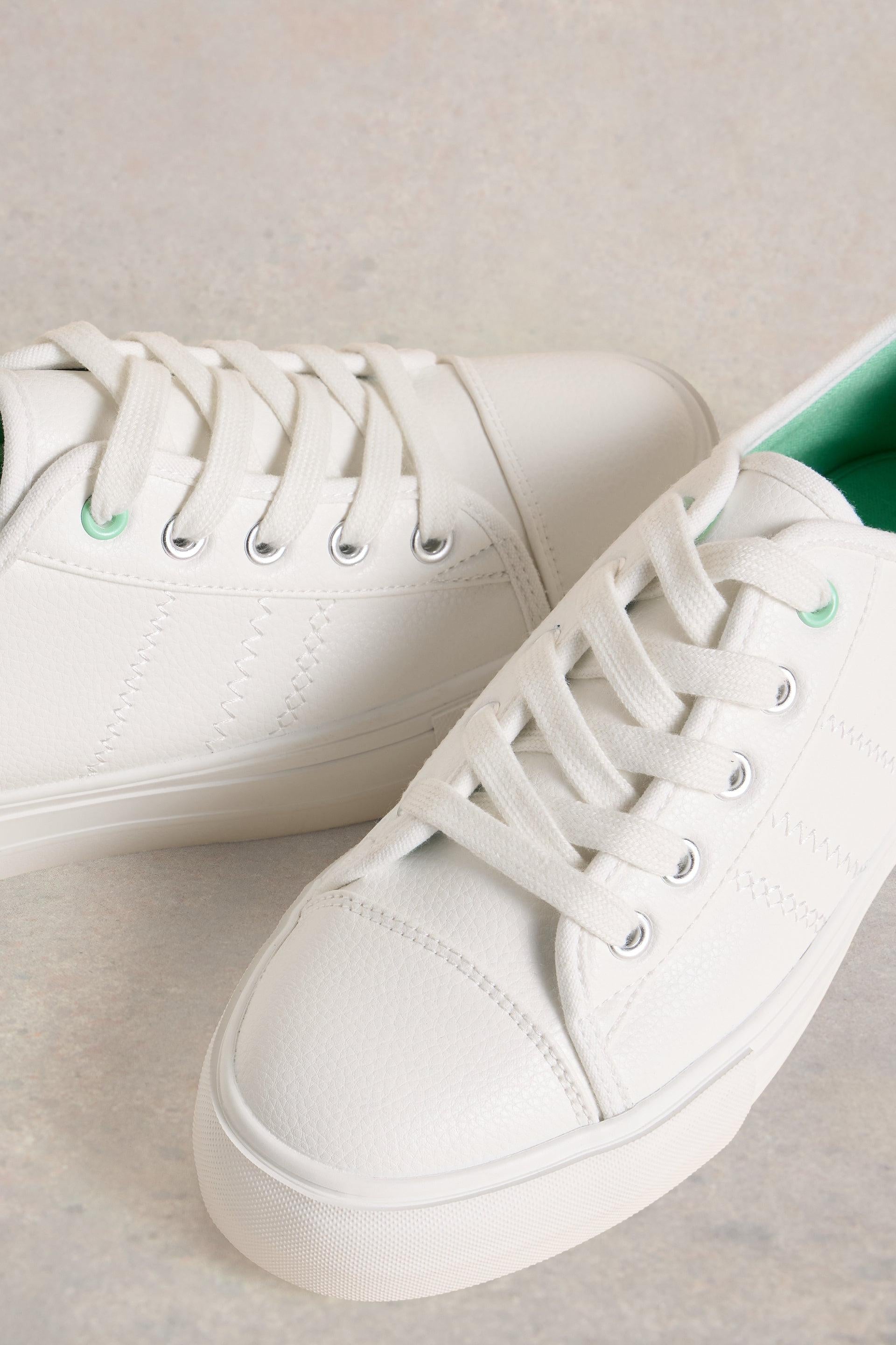 A pair of White Stuff white lace-up sneakers featuring a textured leather finish and subtle green interior lining.
