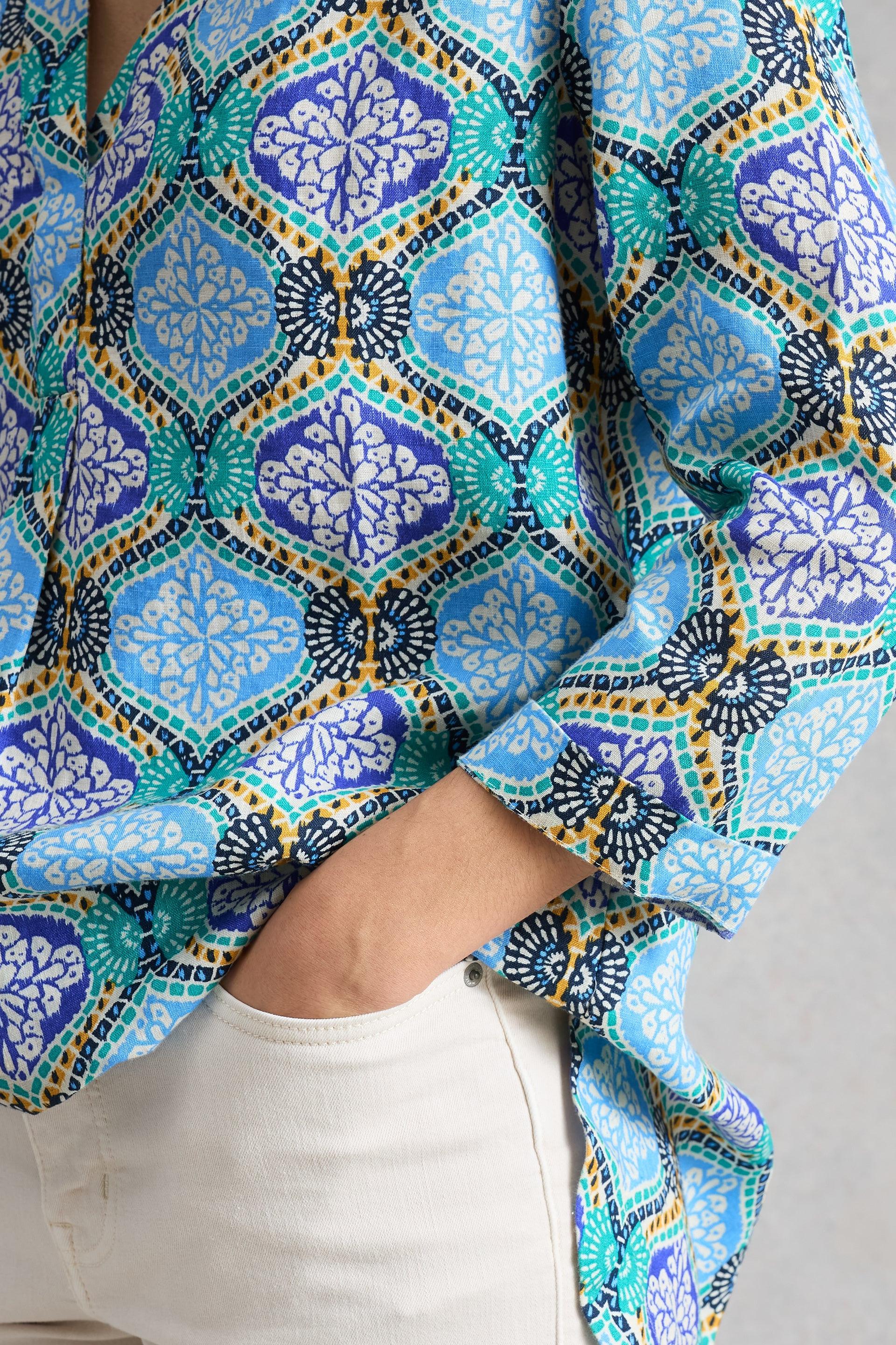 Close-up of a colorful patterned linen tunic with geometric designs on a neutral background