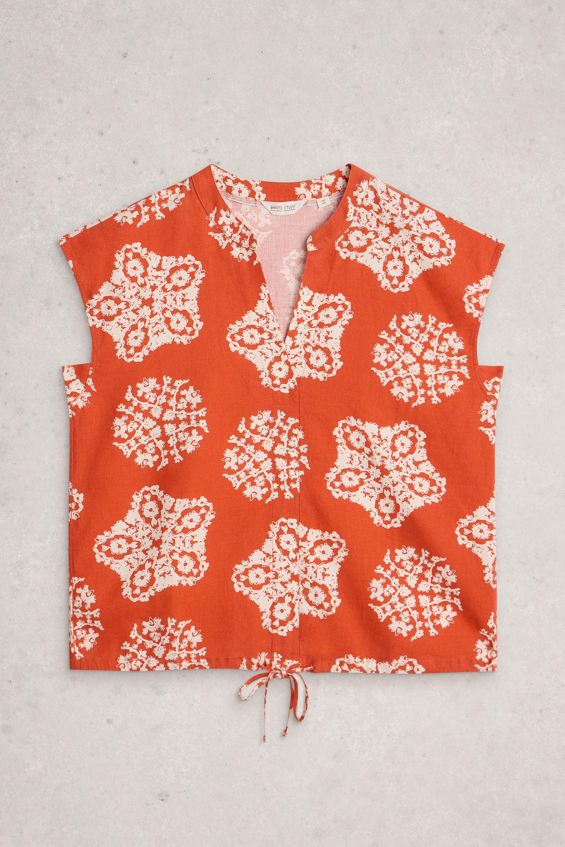 Red sleeveless top with white floral pattern on a light gray background