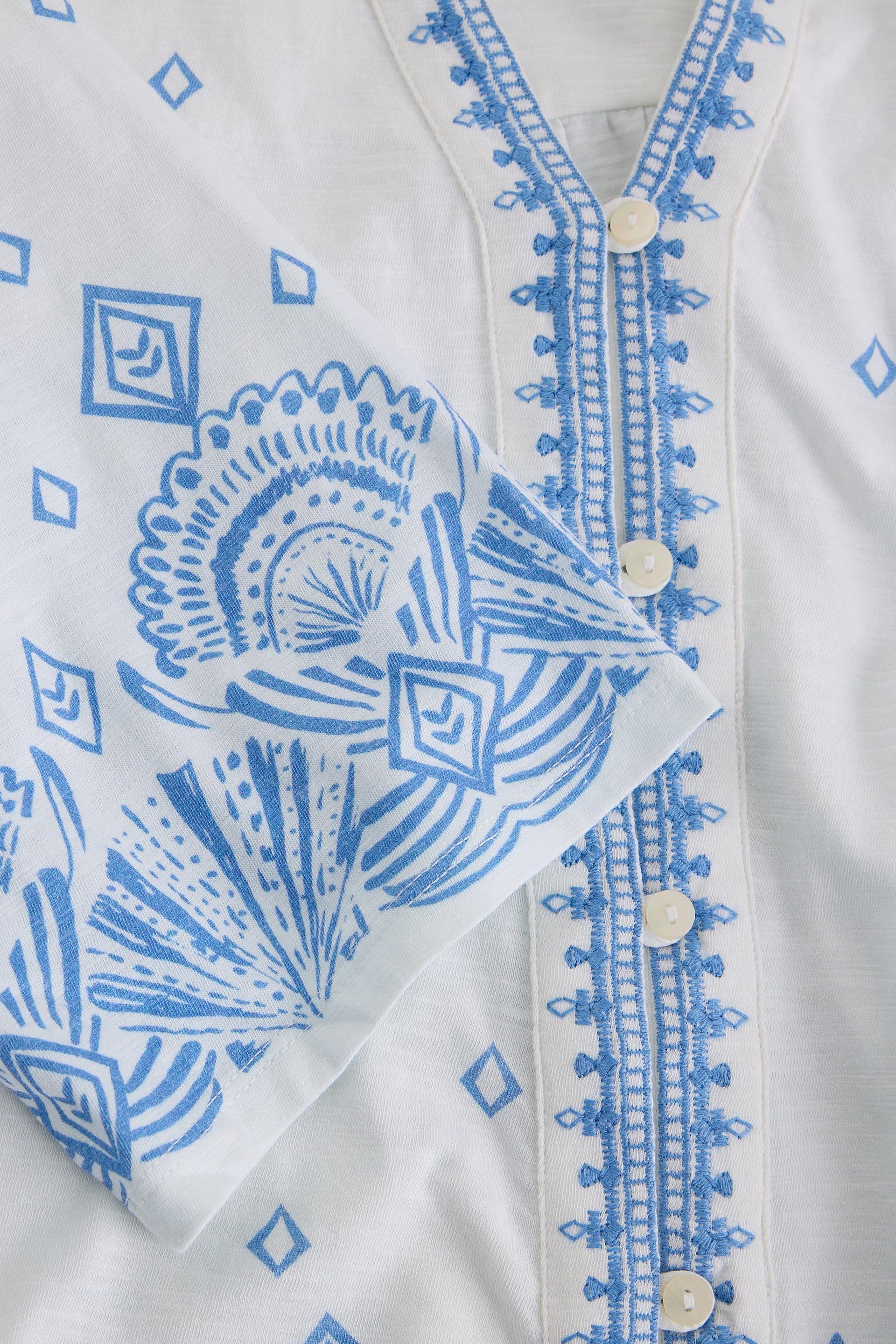 White organic cotton blouse with blue intricate patterns on a white background