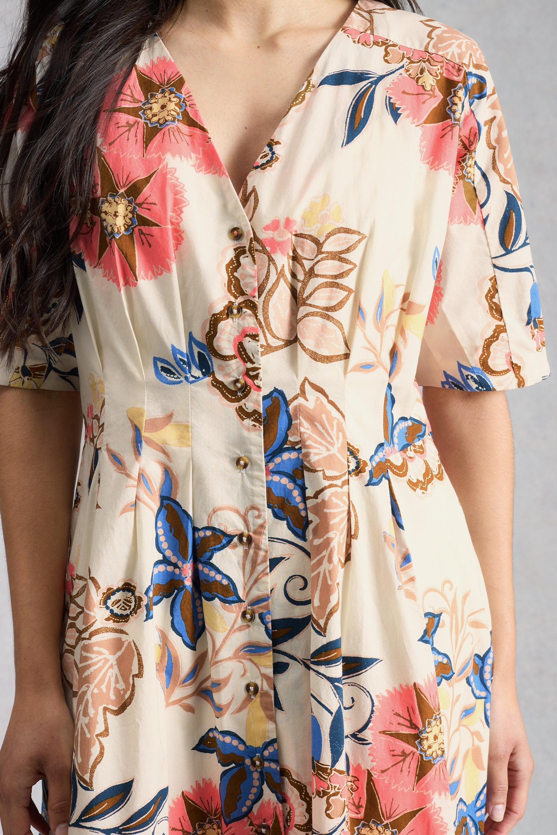 Close-up of a model wearing a floral White Stuff dress with colourful patterns on a neutral background