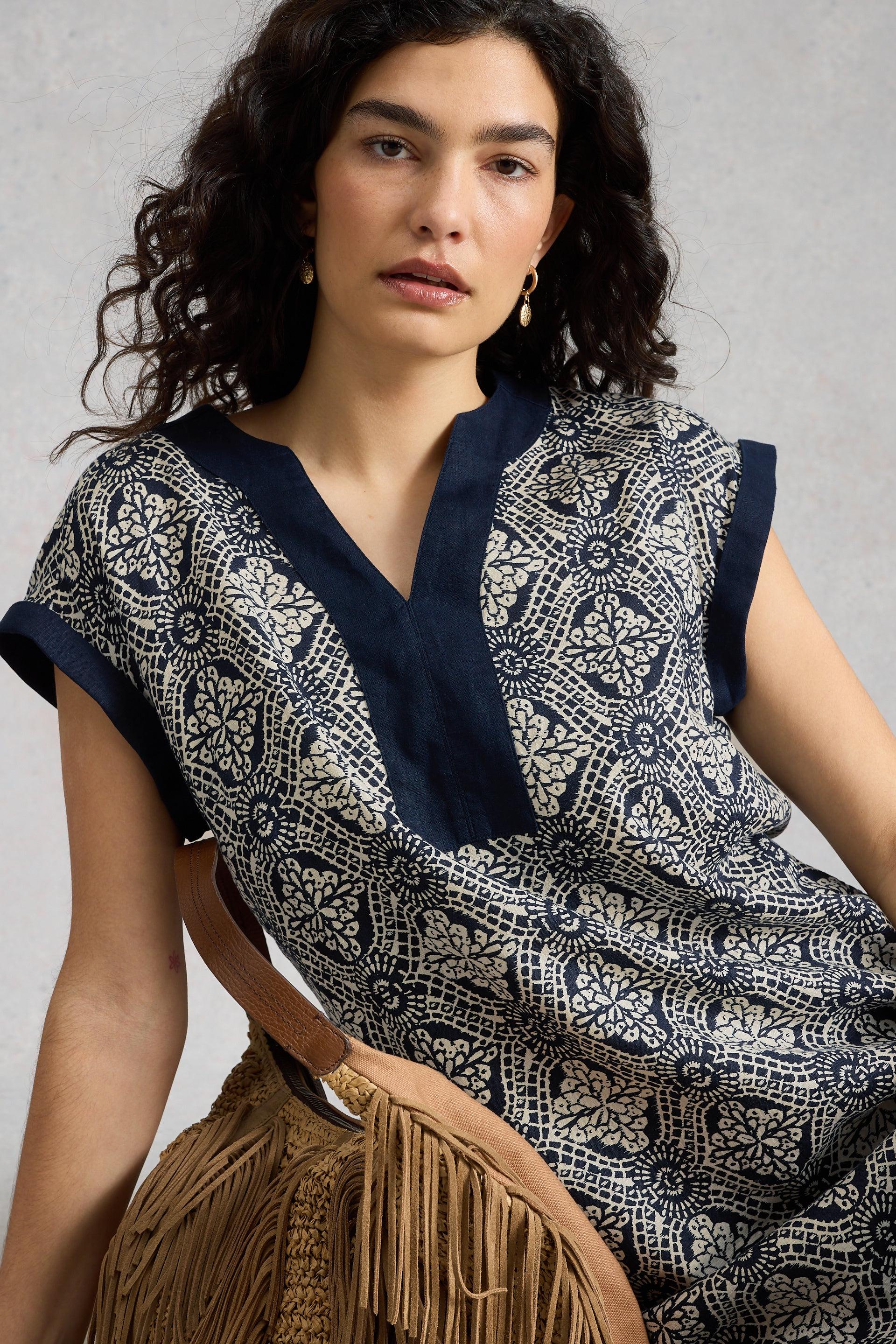 Woman wearing a patterned linen dress with a neutral background