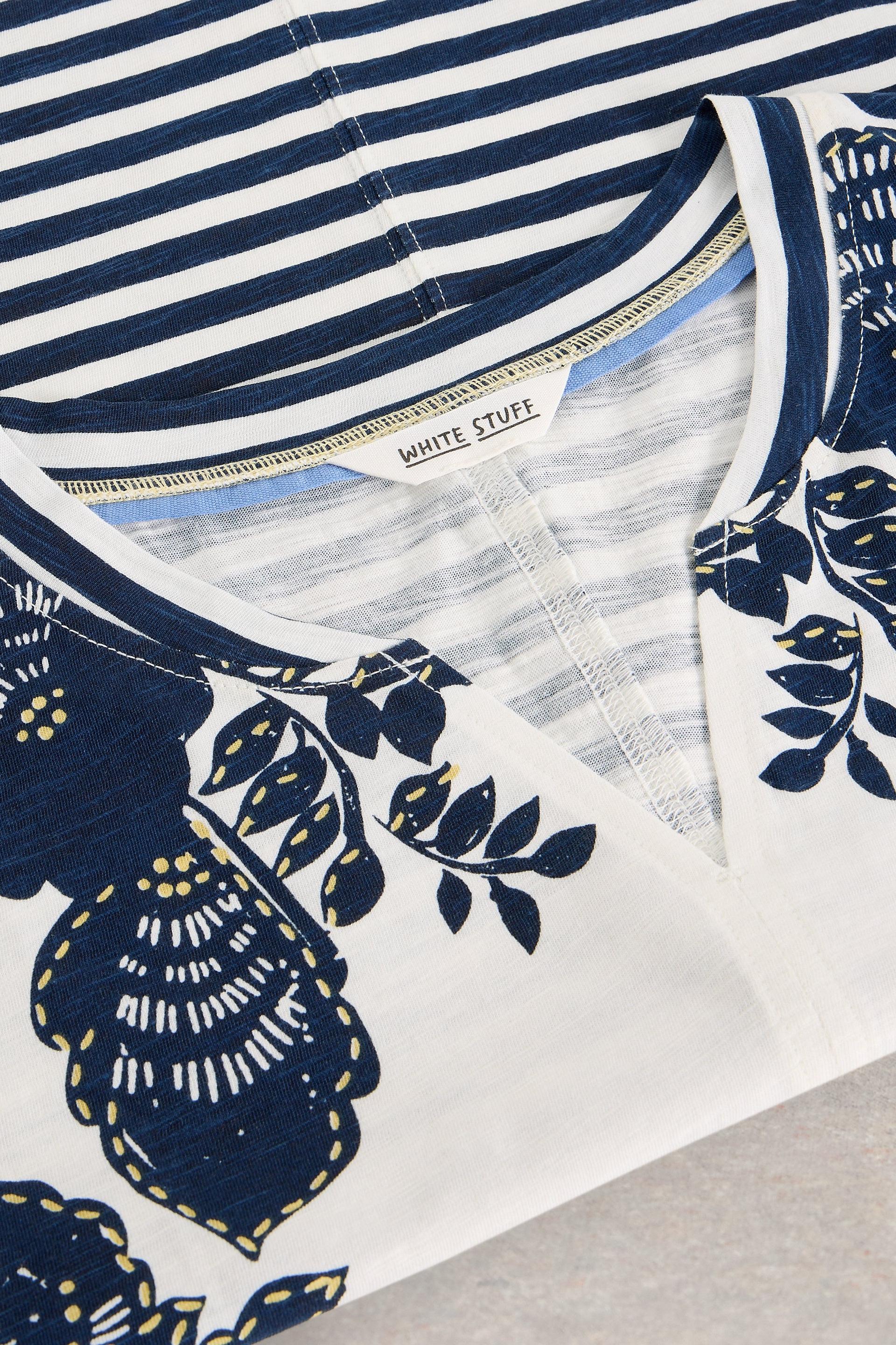 Navy and white striped t-shirt with floral patterns on a neutral background