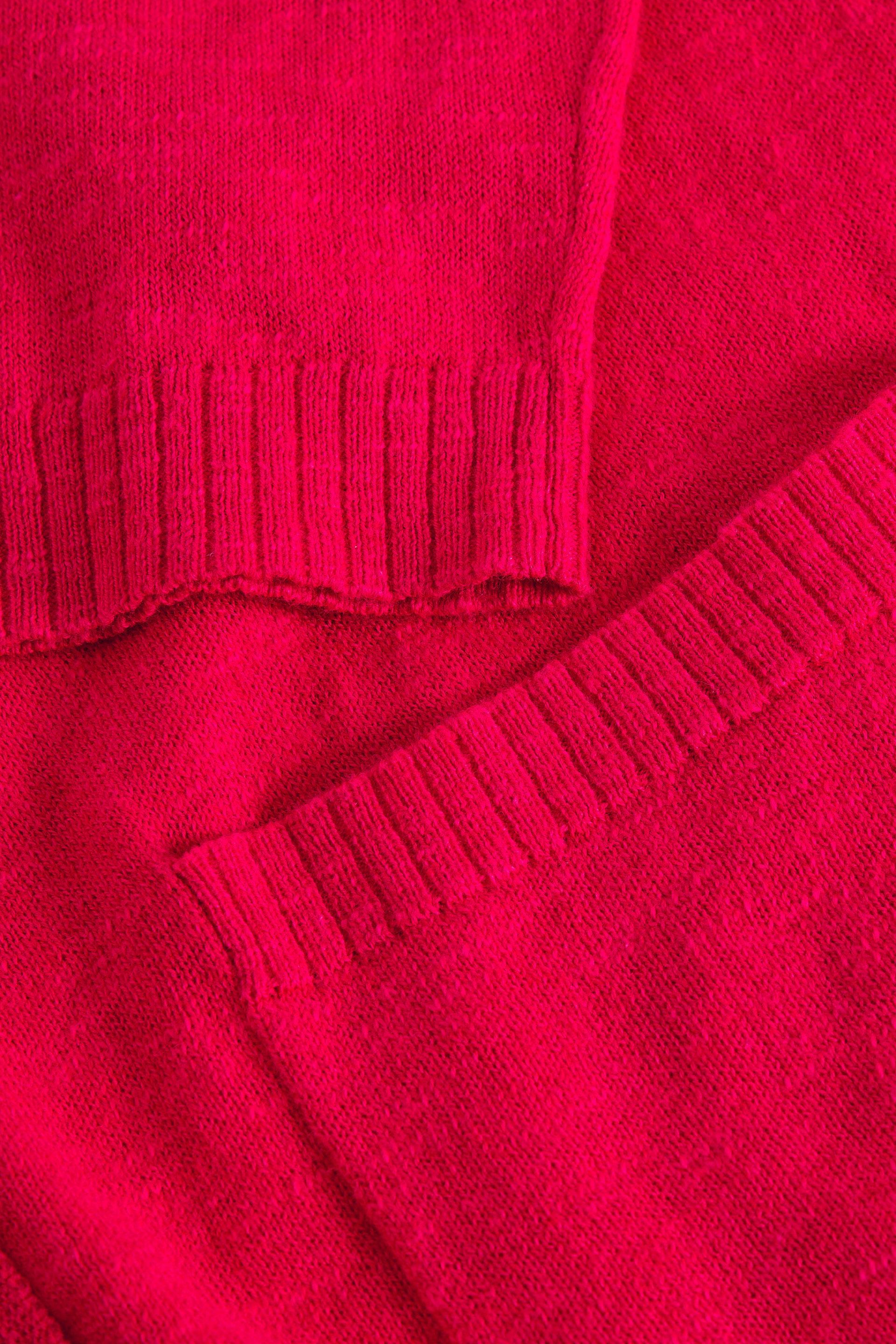 Close-up of a pink organic cotton knitted sweater with a focus on texture and pattern.