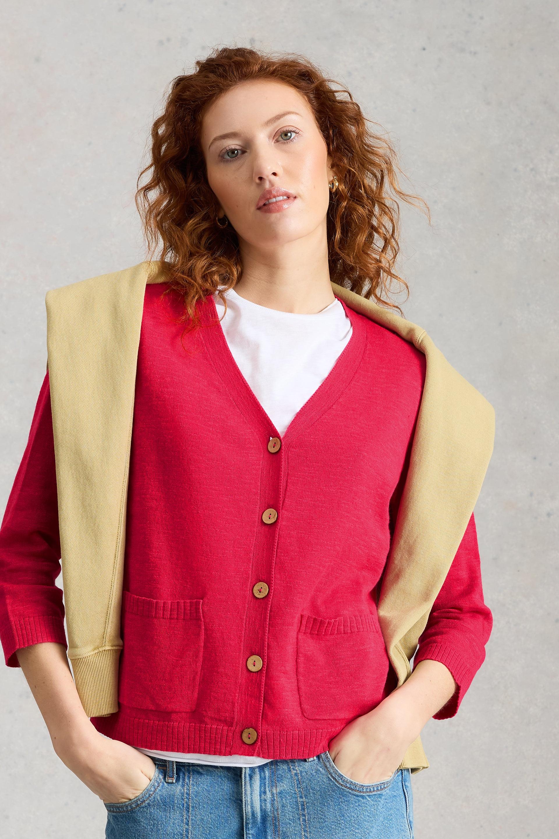 Woman wearing a pink organic cotton cardigan against a gray background