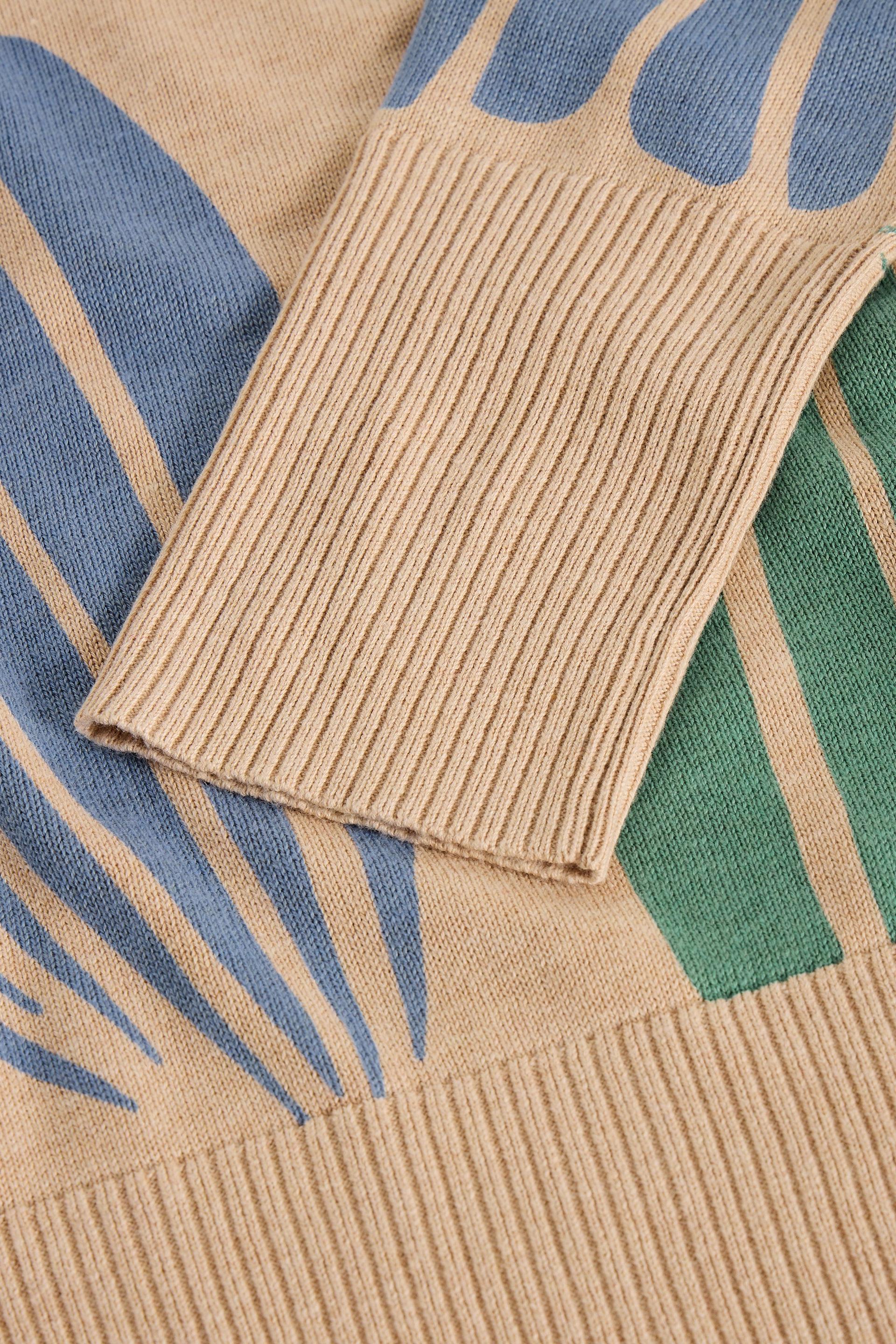 Close-up of a beige organic cotton sweater with blue and green abstract patterns