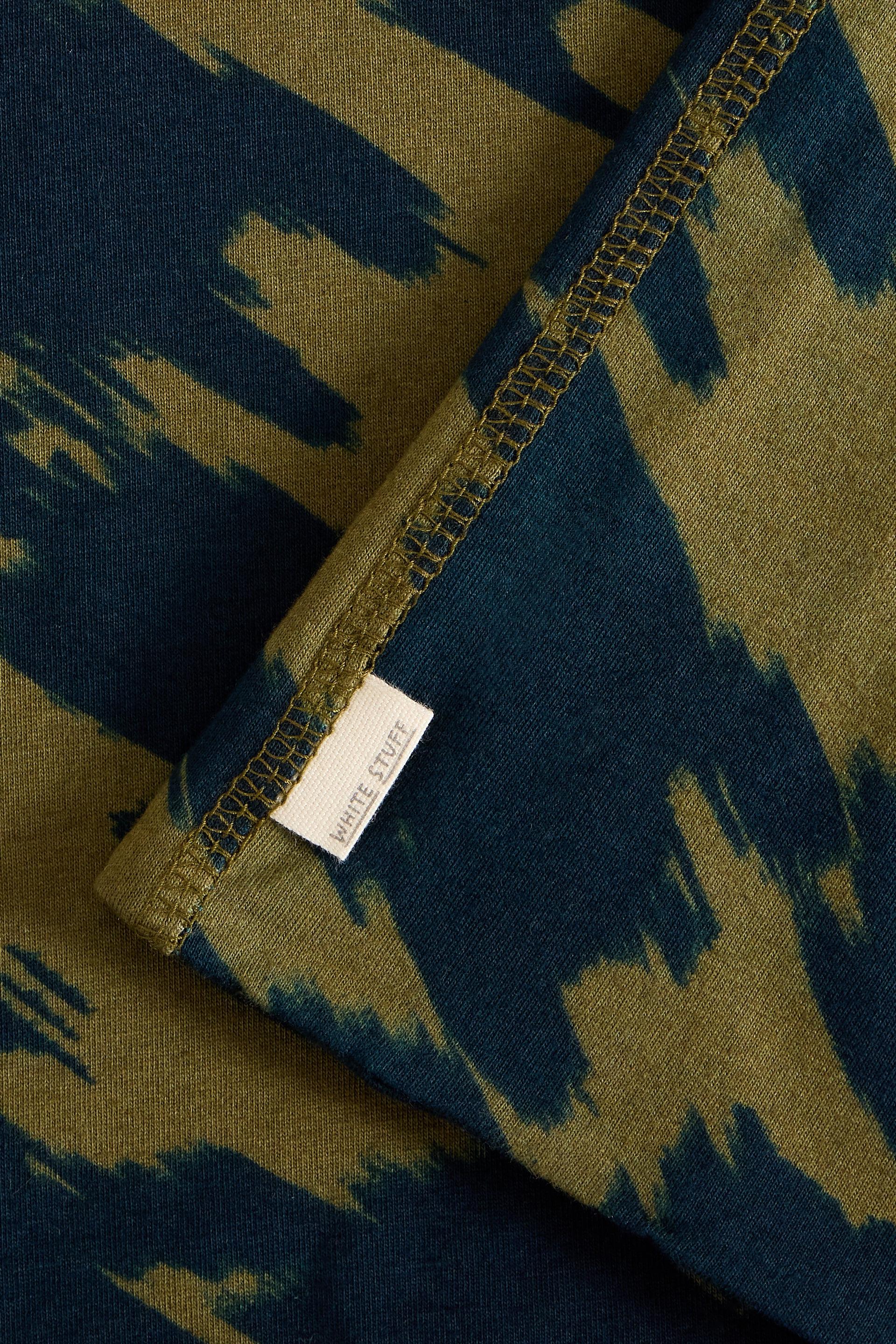 Close up of olive green and navy abstract pattern fabric with a White Stuff clothing brand label