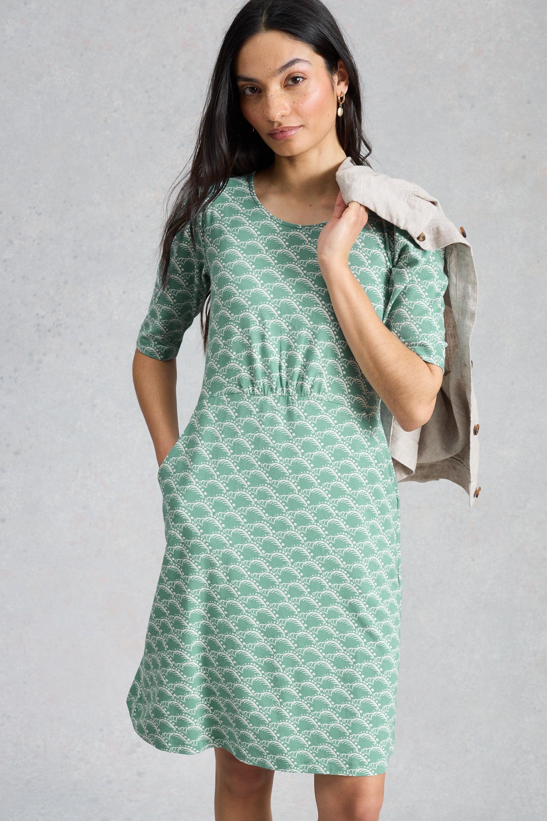 Woman wearing a green patterned dress against a gray background