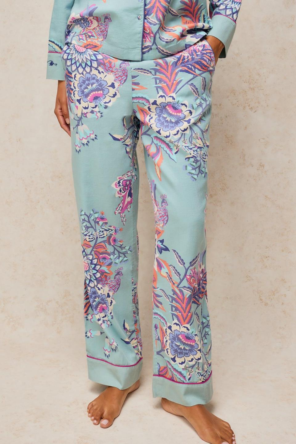 A person wearing blue organic cotton pyjama bottoms with a floral print pattern against a neutral background.