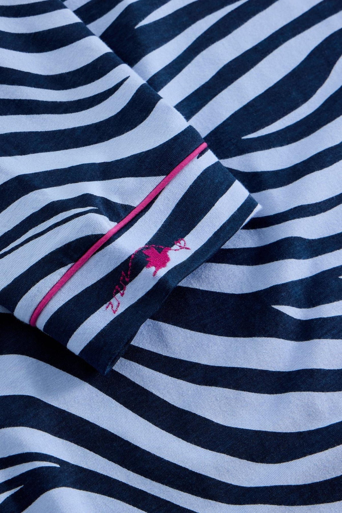 Close-up of a White Stuff organic cotton blue zebra print nightdress sleeve with pink piping and embroidered logo.