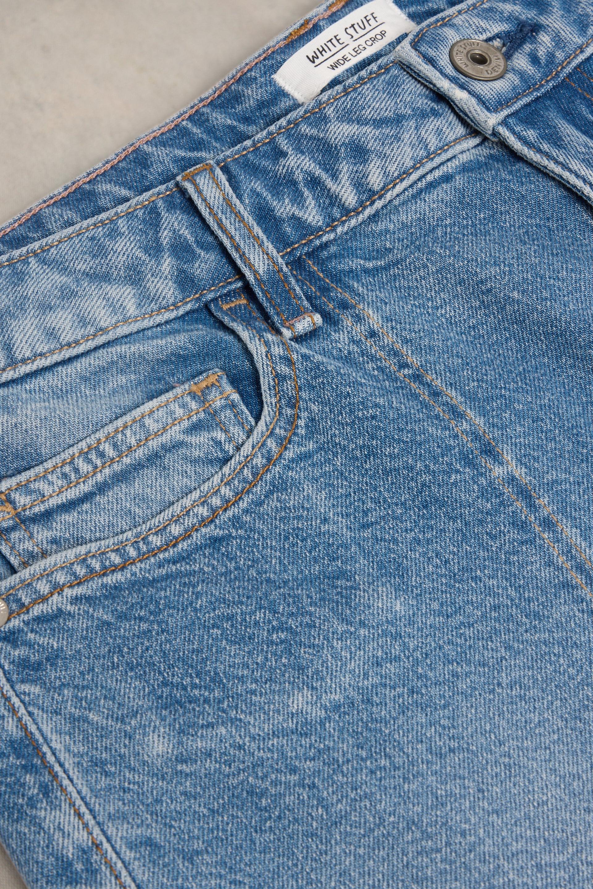 Close-up of a White Stuff wide leg denim jean waistband with a brand label and metal button detail