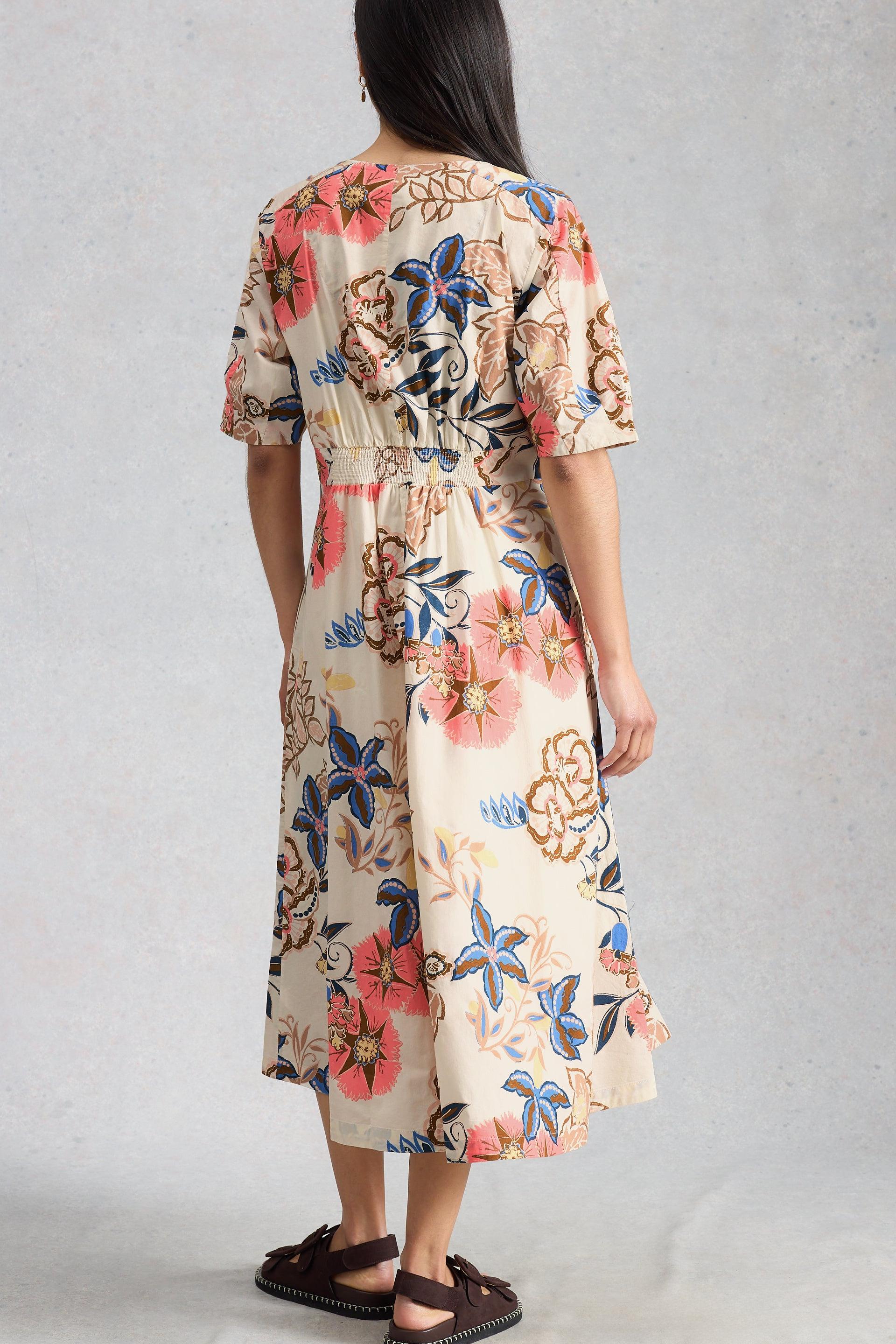 Woman wearing a floral organic cotton dress with a plain background