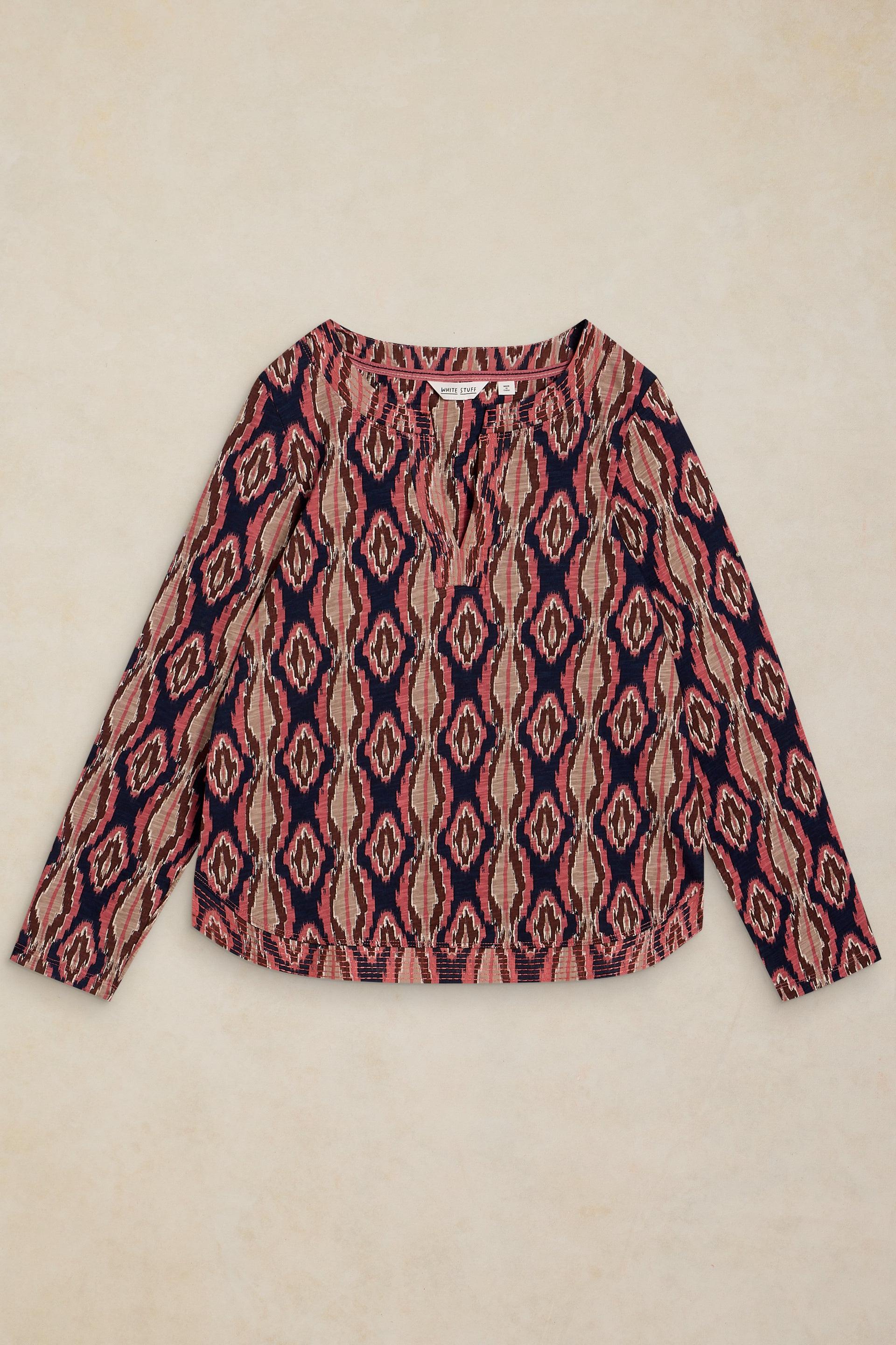 A long-sleeve knit top with a geometric diamond pattern in navy blue, dusty pink, and beige, laid flat on a textured beige background.