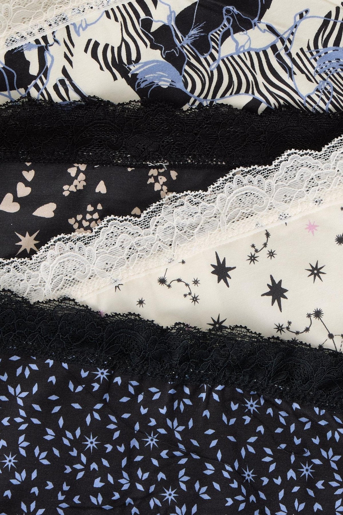 A stacked collection of White Stuff organic cotton knickers featuring various patterns and black and white lace trim.