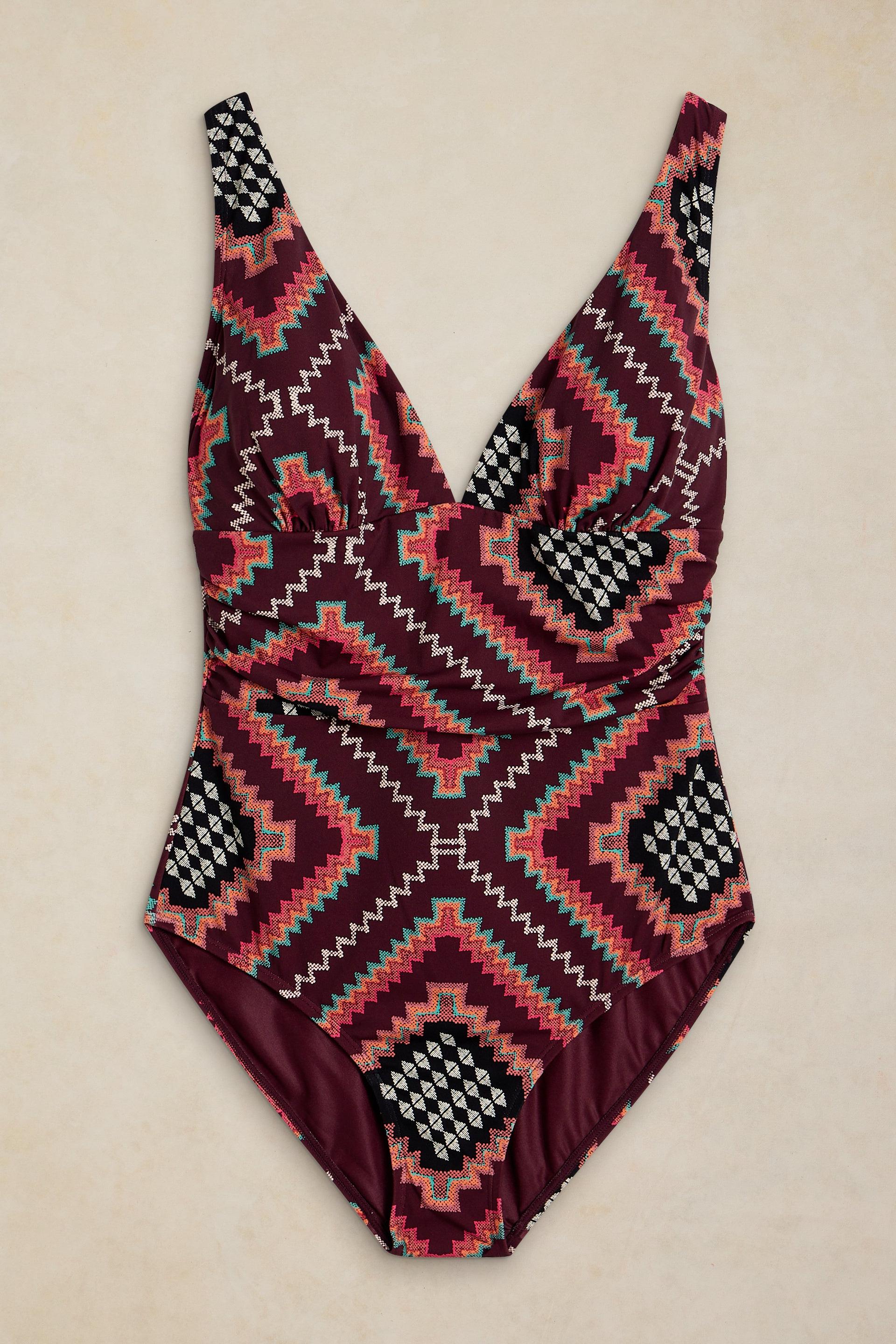 White Stuff one-piece swimsuit featuring a burgundy base with a colorful geometric tribal print and V-neckline