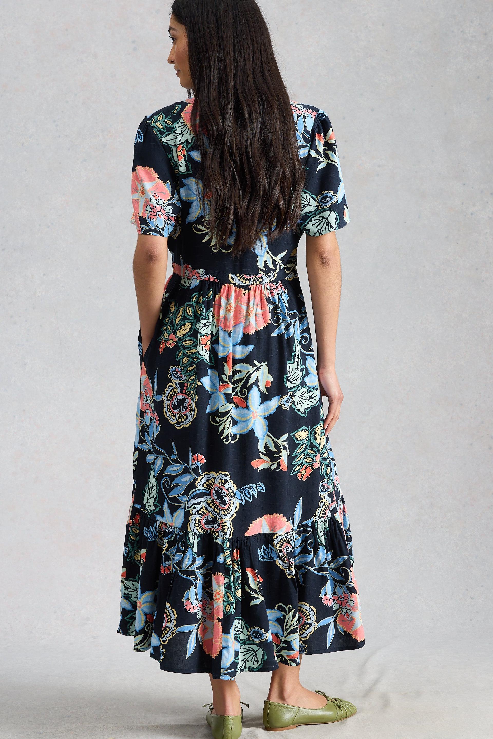 Woman wearing a floral sustainable dress against a plain background