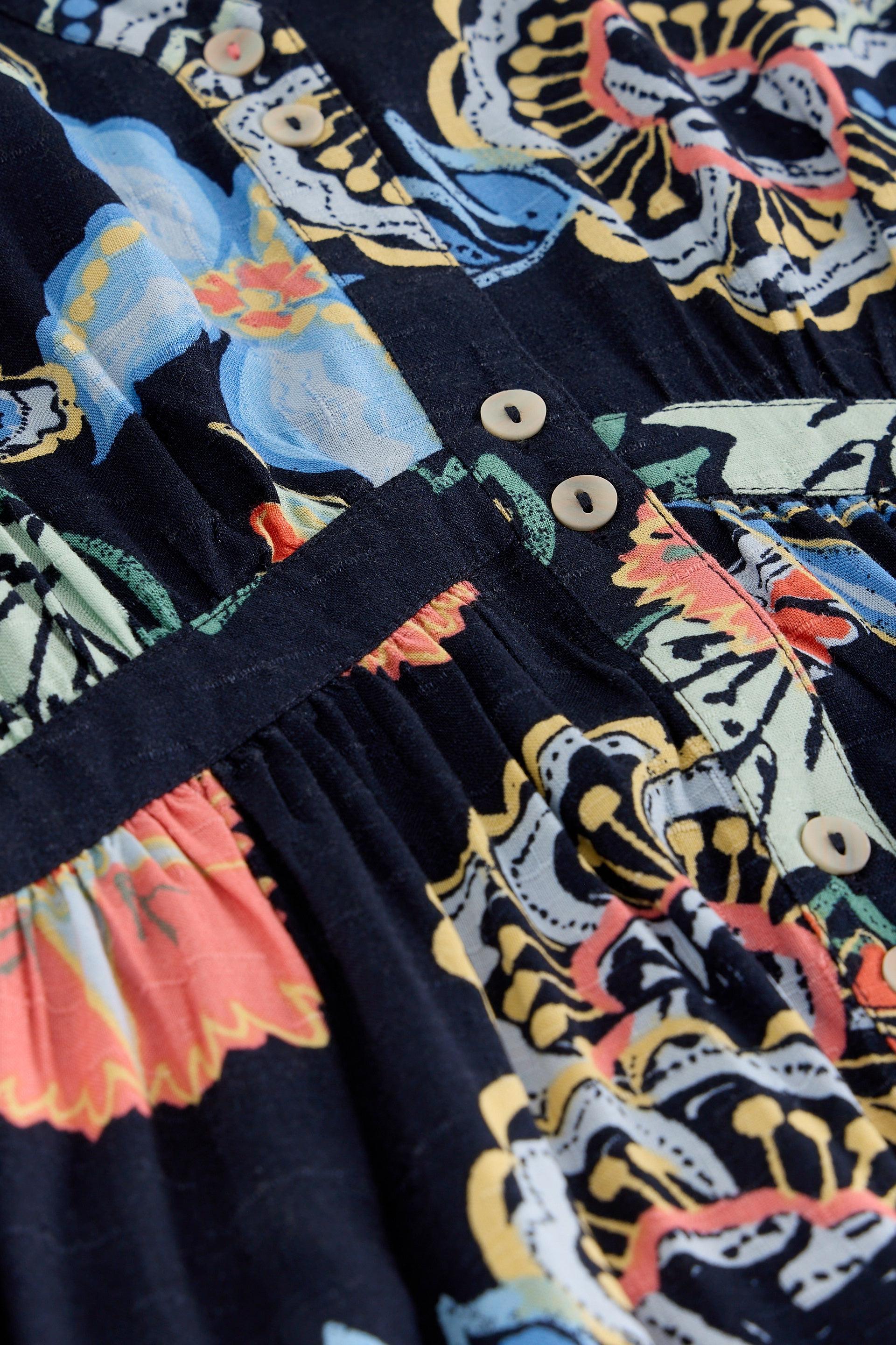 Close-up of a colourful patterned fabric with floral and abstract designs on a navy background.