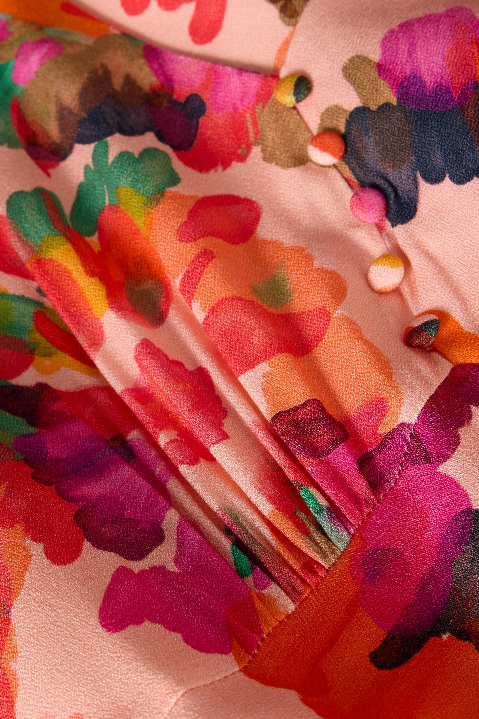 Close-up of a pink floral occasion dress featuring vibrant painterly floral patterns and fabric-covered buttons.