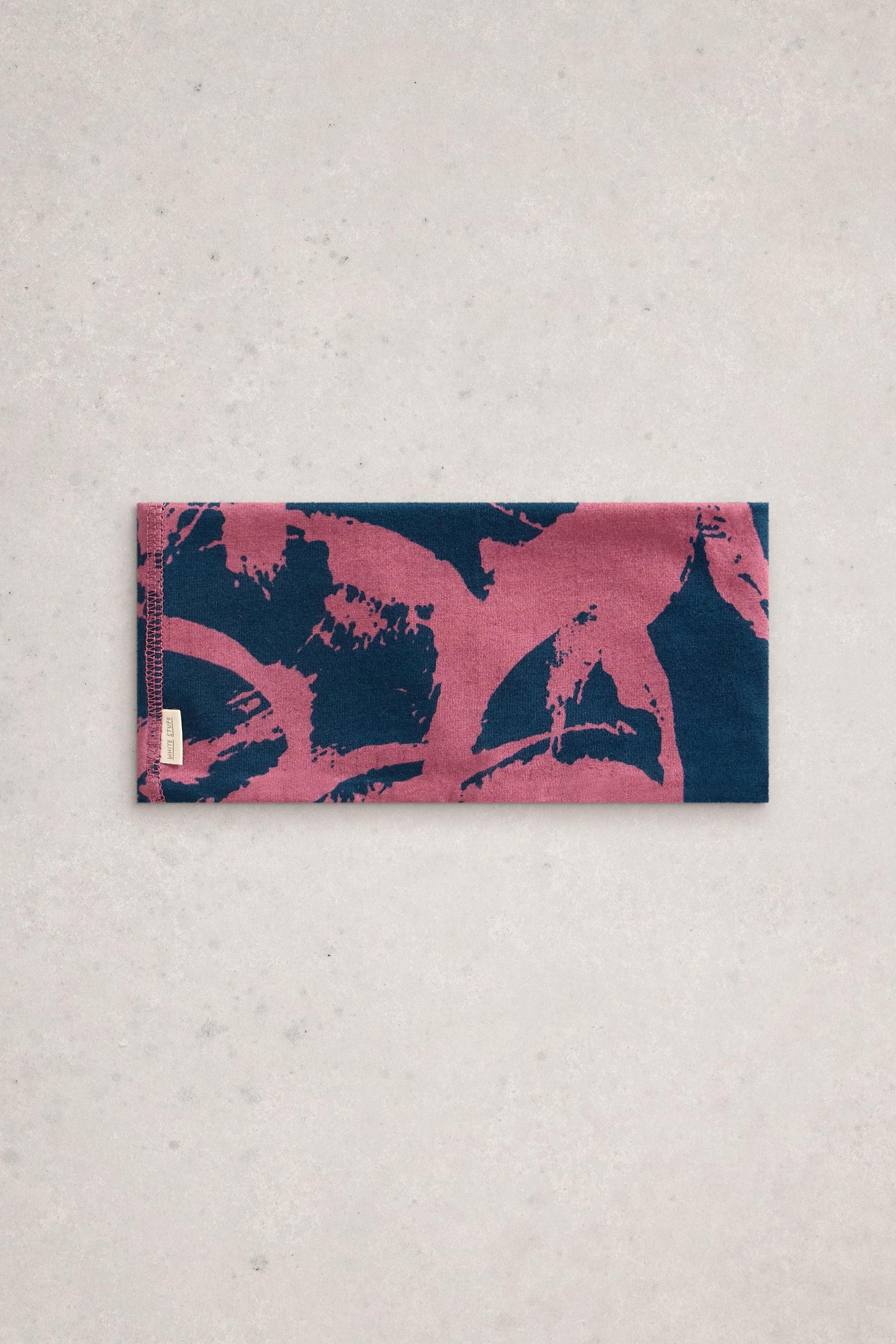 A rectangular White Stuff headband with a dark blue and pink abstract brushstroke print on a light gray background