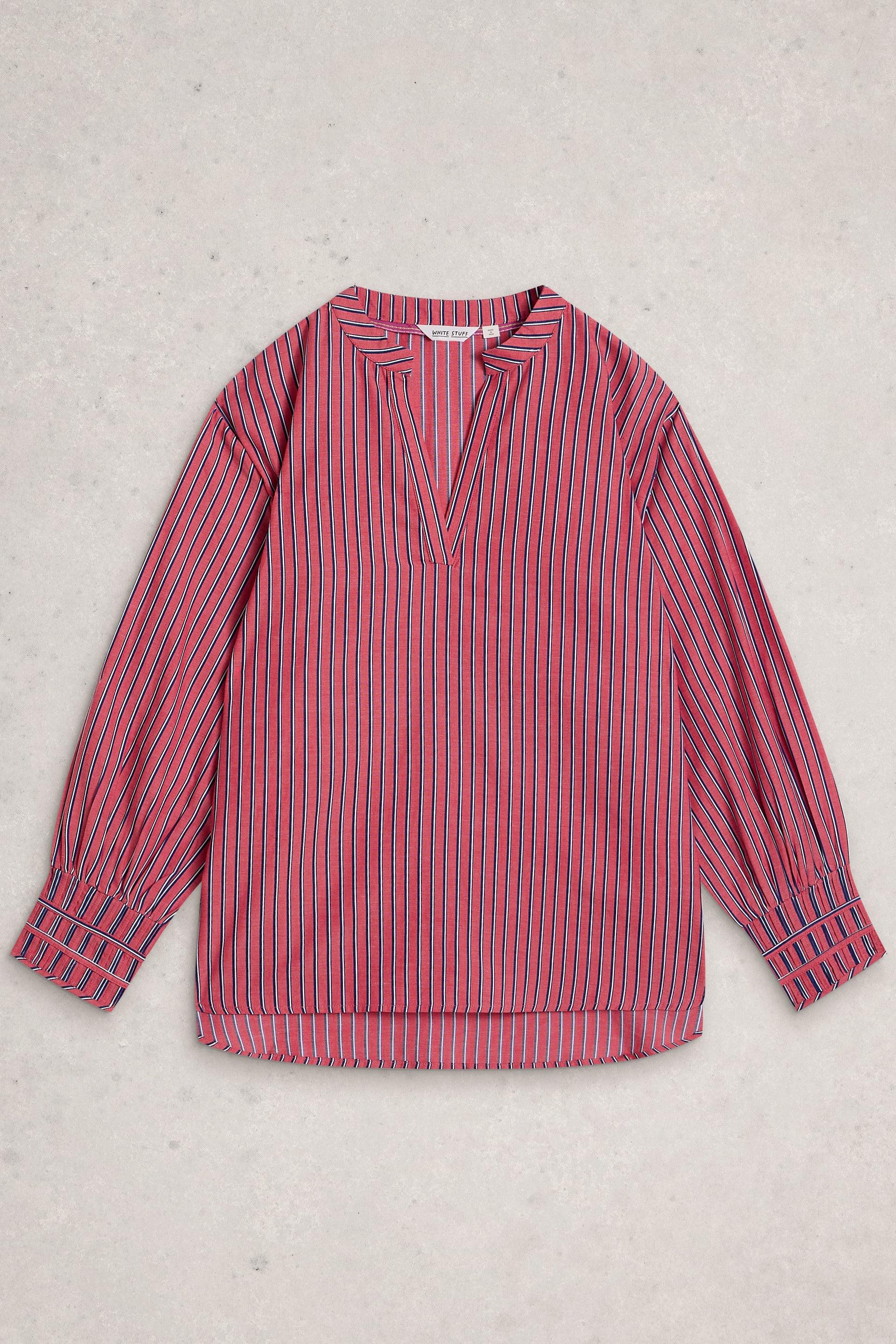 A pink and blue vertically striped long-sleeve blouse with a split V-neckline, laid flat on a textured light gray background.