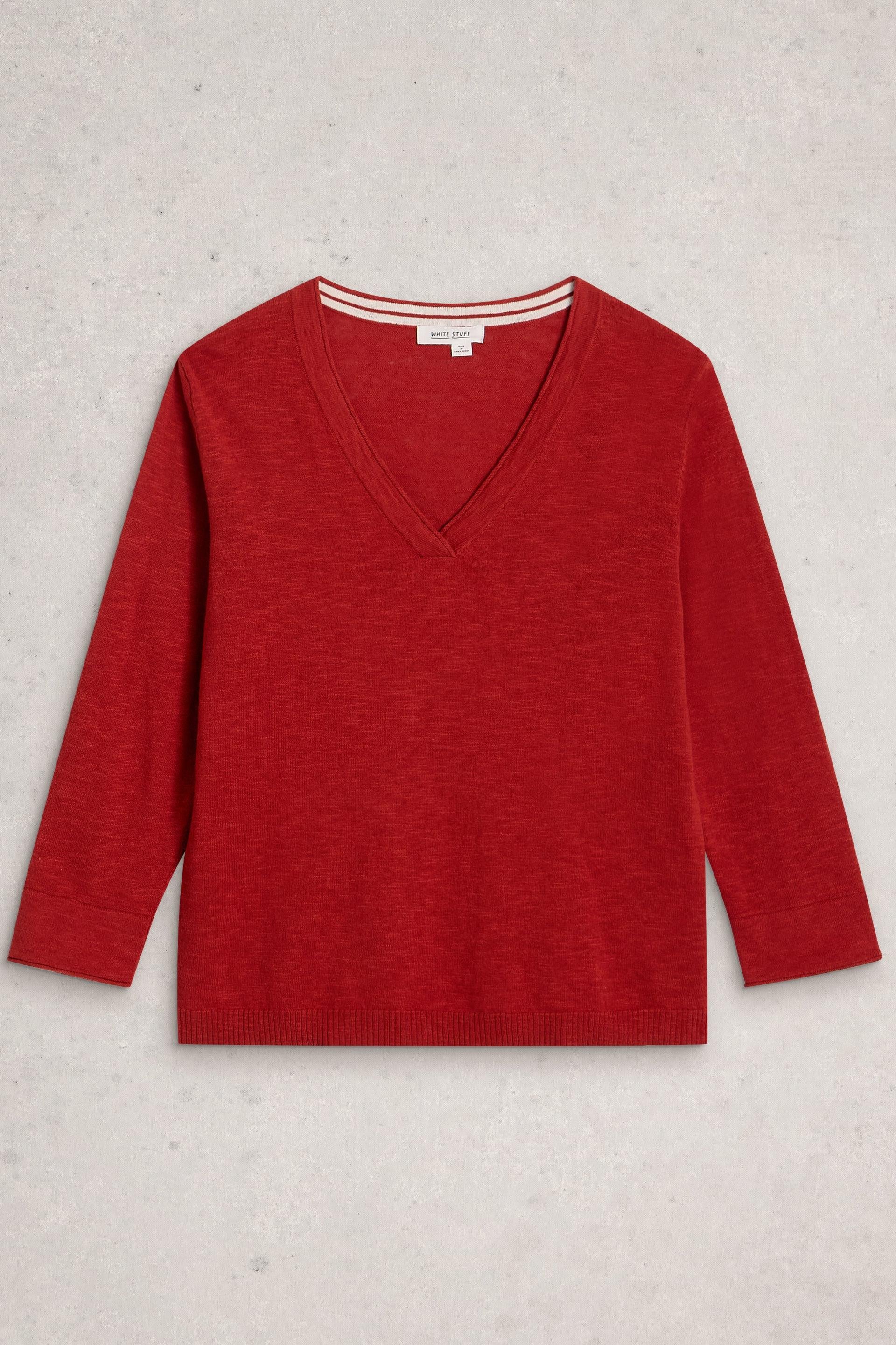 A red long-sleeve V-neck sweater by White Stuff made from organic cotton, displayed flat against a grey background.