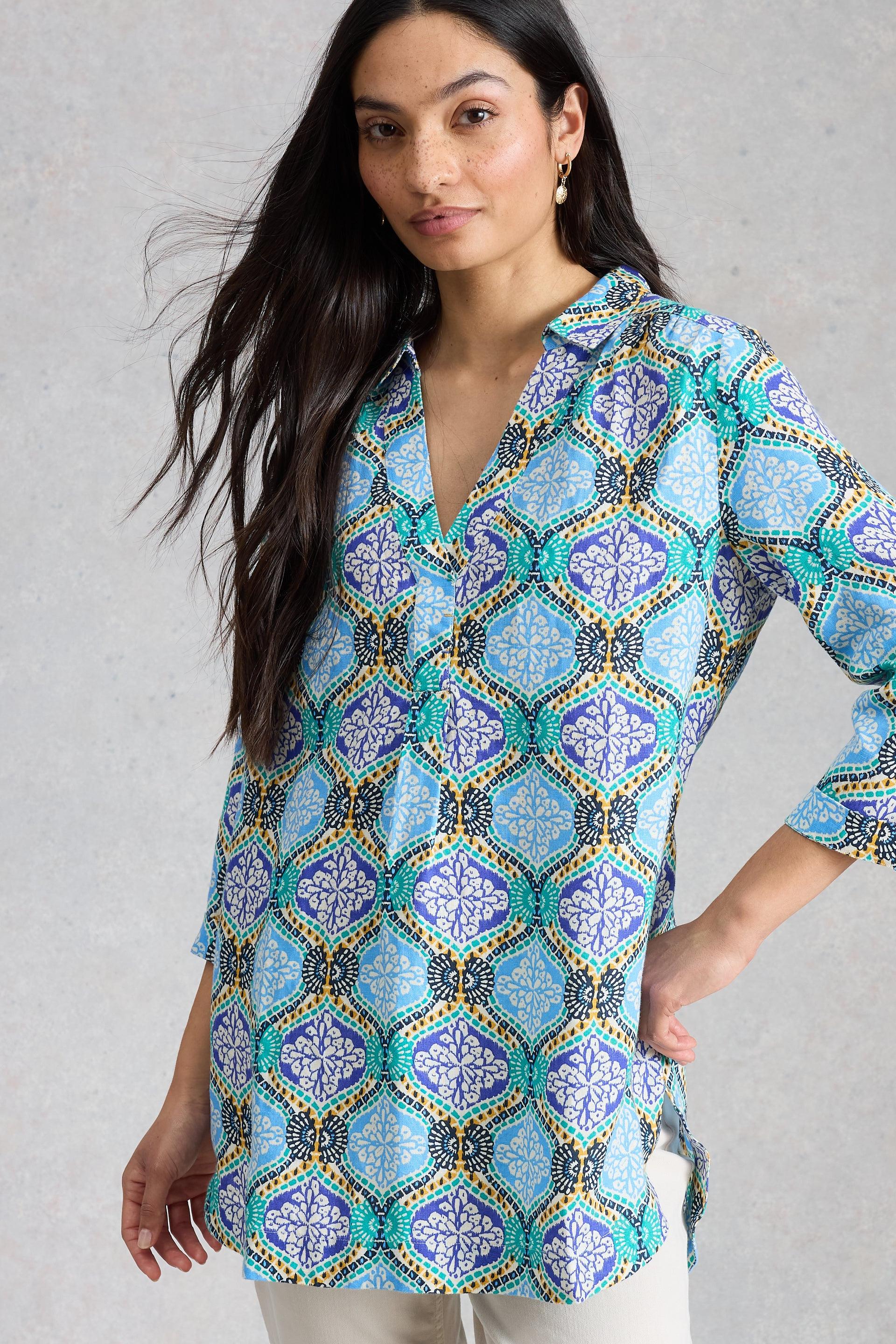 Woman wearing a patterned blue linen tunic against a gray background